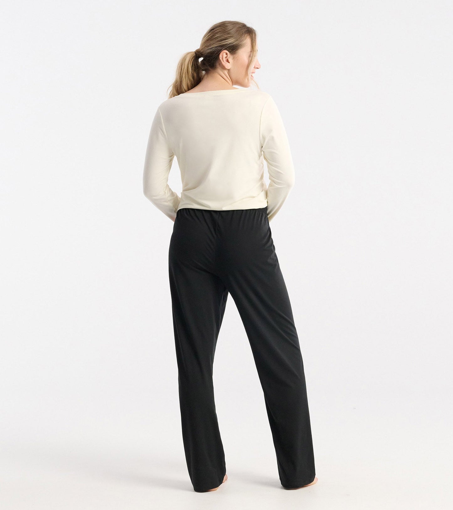 Long sleeve cream cami t-shirt with lace detail, worn with black pants, viewed from the back.