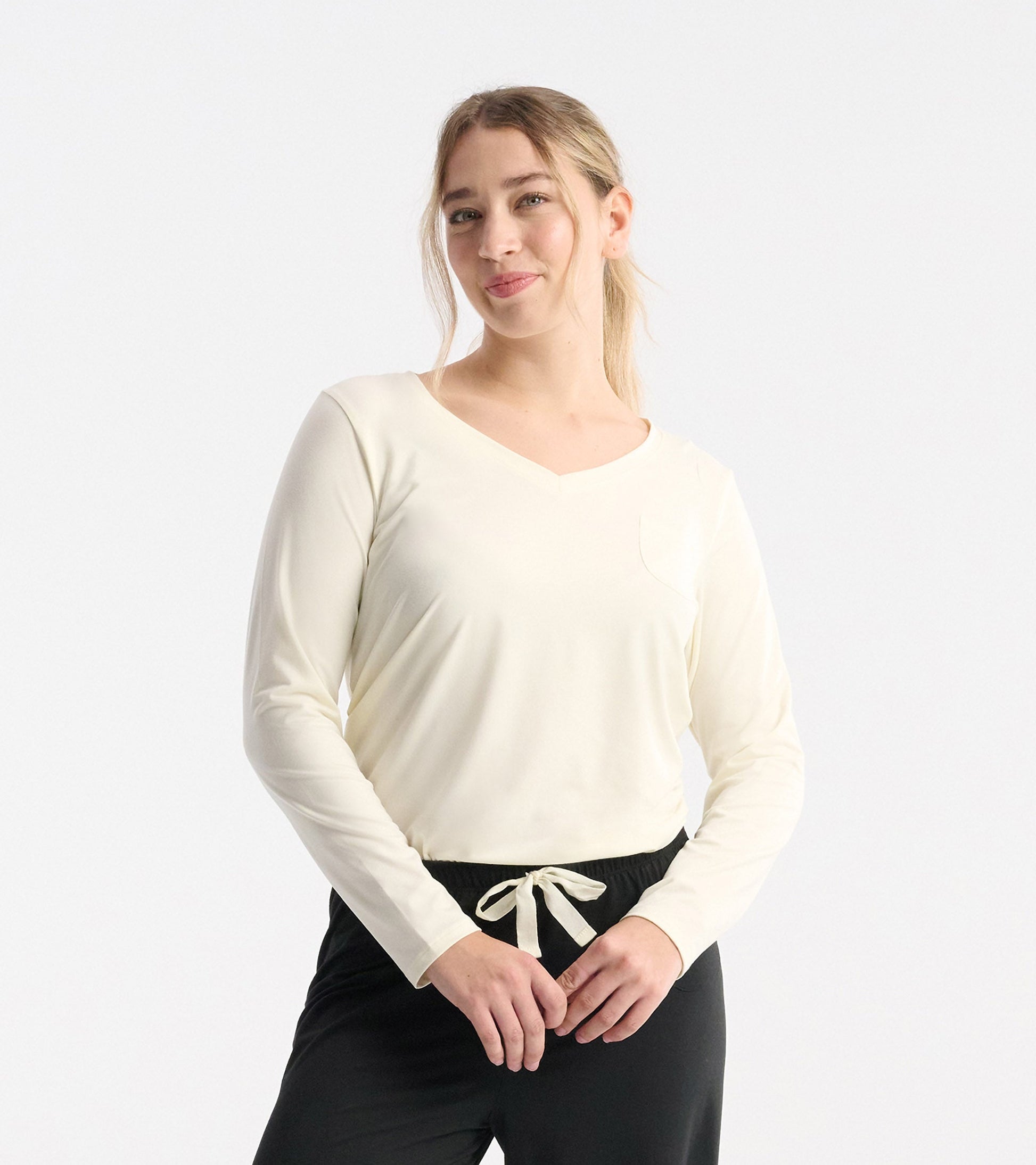 Light cream long sleeve t-shirt with a v-neck and pocket, styled with black drawstring pants.