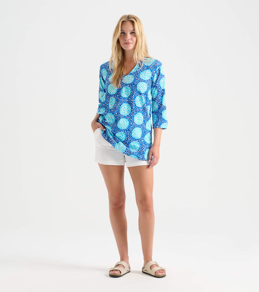 Blue tunic with a circular pattern, featuring a V-neck and three-quarter sleeves, paired with white shorts.
