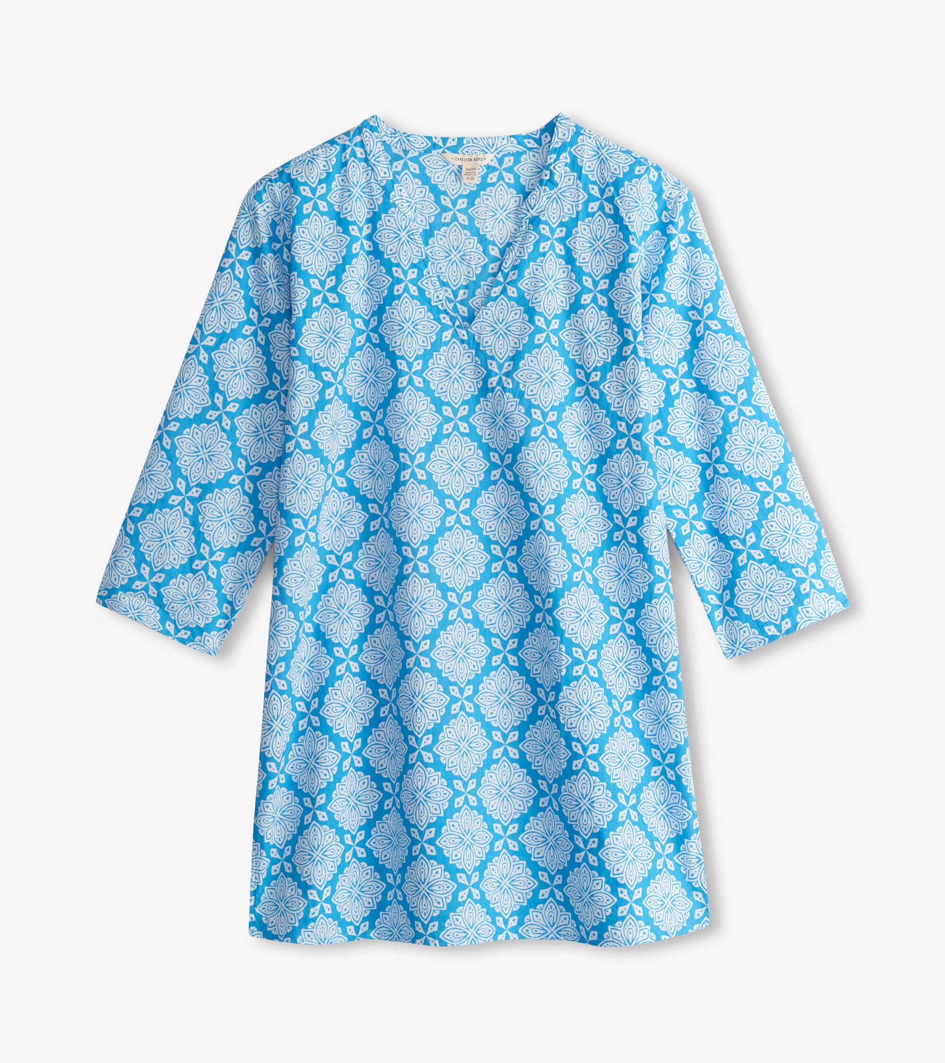 Blue tunic featuring a white floral pattern, with a V-neck and three-quarter sleeves.