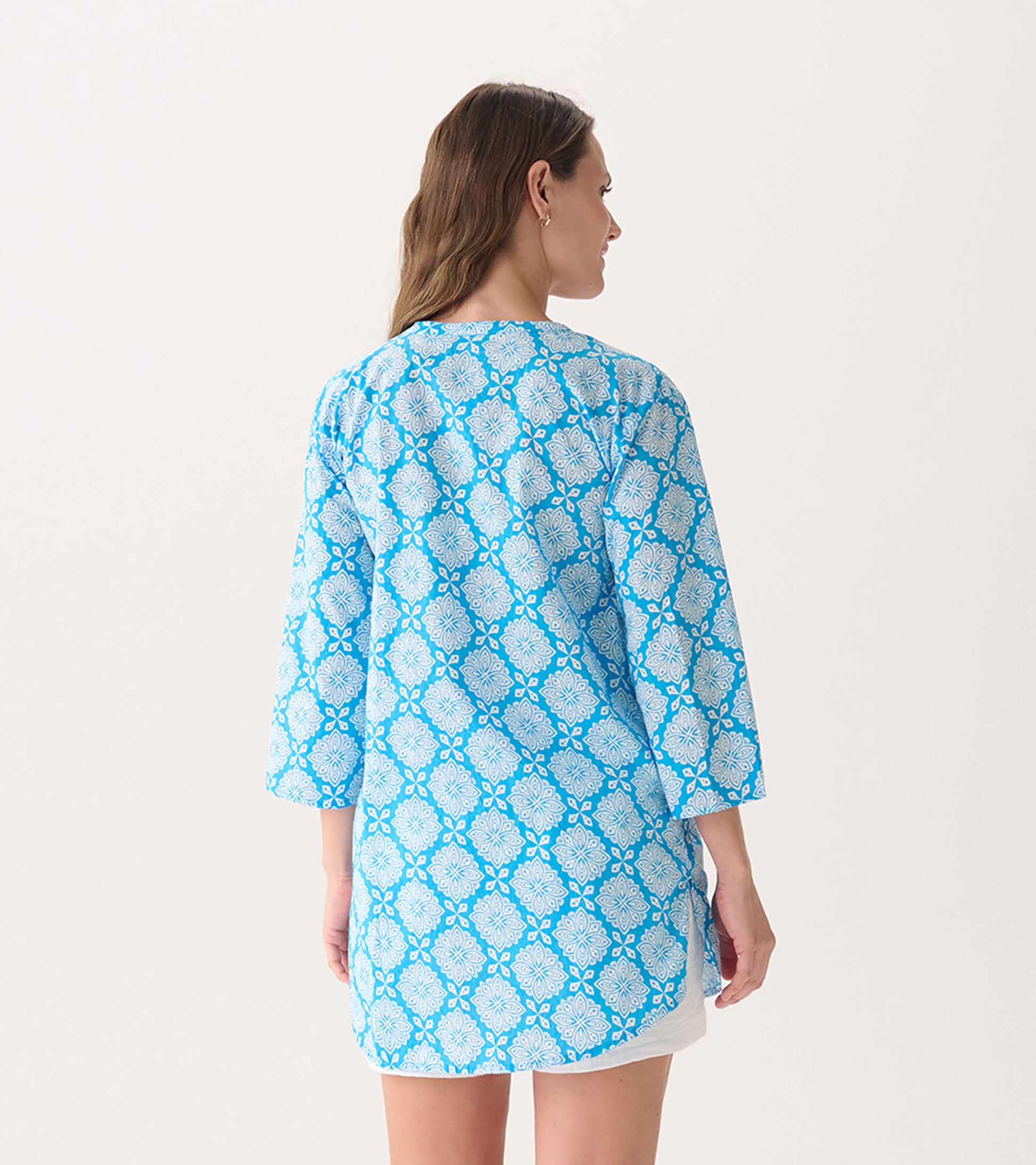 Blue tunic with a white floral pattern, featuring three-quarter sleeves and a relaxed fit, viewed from the back.
