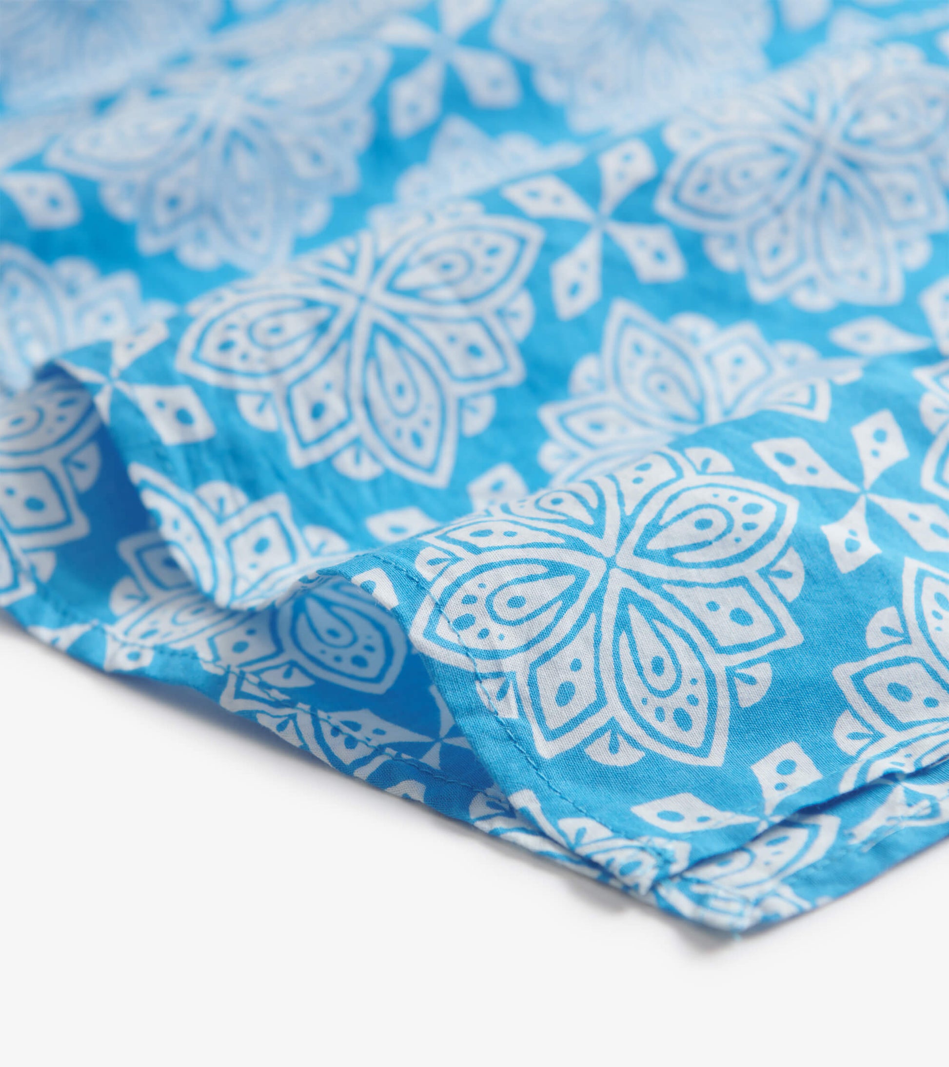 Blue tunic featuring a white floral pattern, showcasing a lightweight fabric with a relaxed fit.