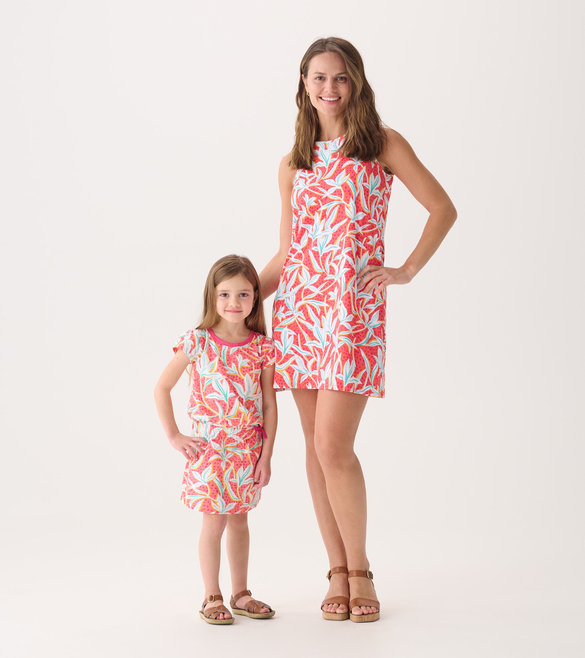 Floral summer dress featuring a vibrant leafy pattern in pink and blue, modeled by an adult and a child.