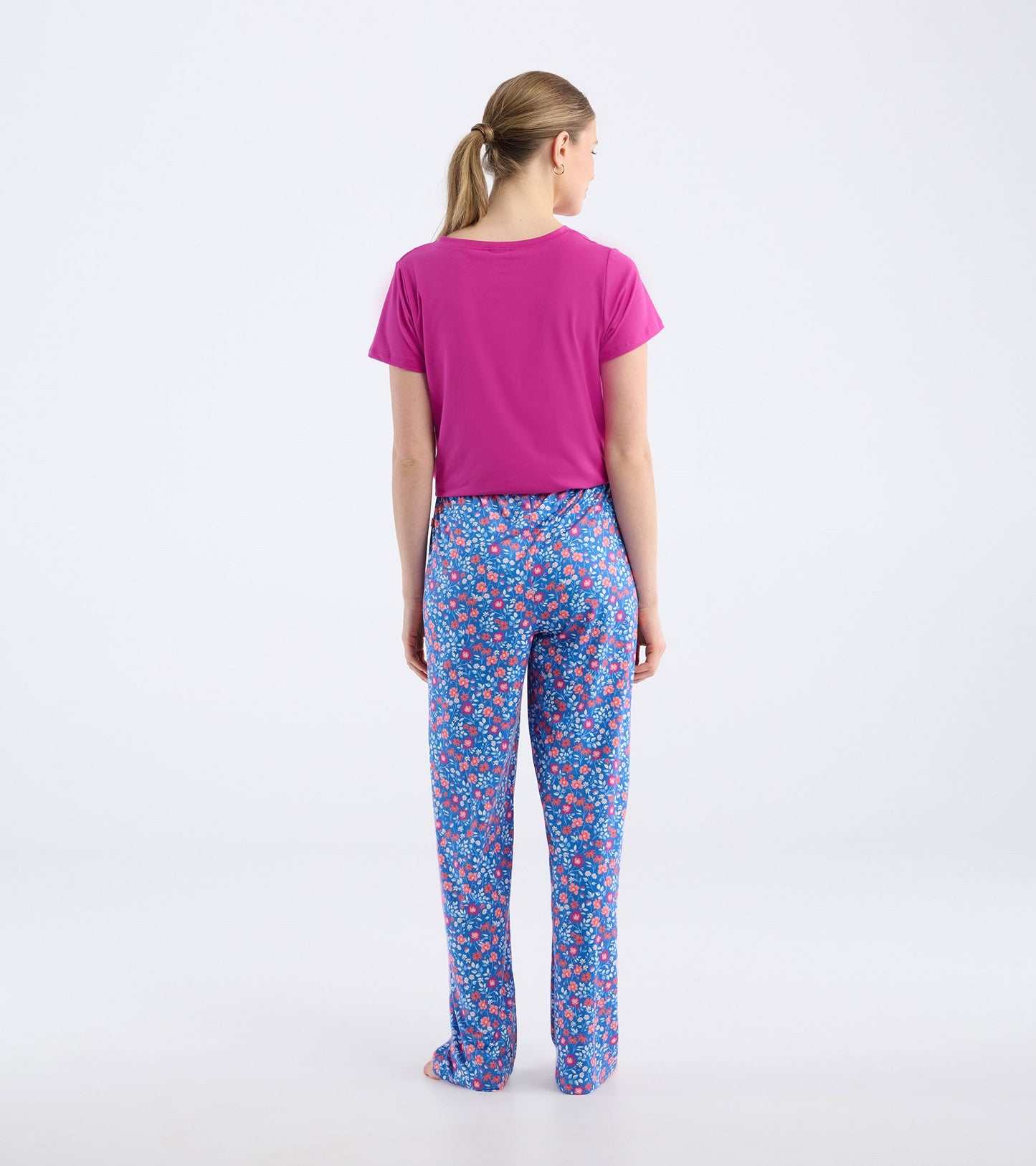 Back view of women's pajama pants featuring a vibrant floral pattern in blue, pink, and white, made from soft polyknit mater…
