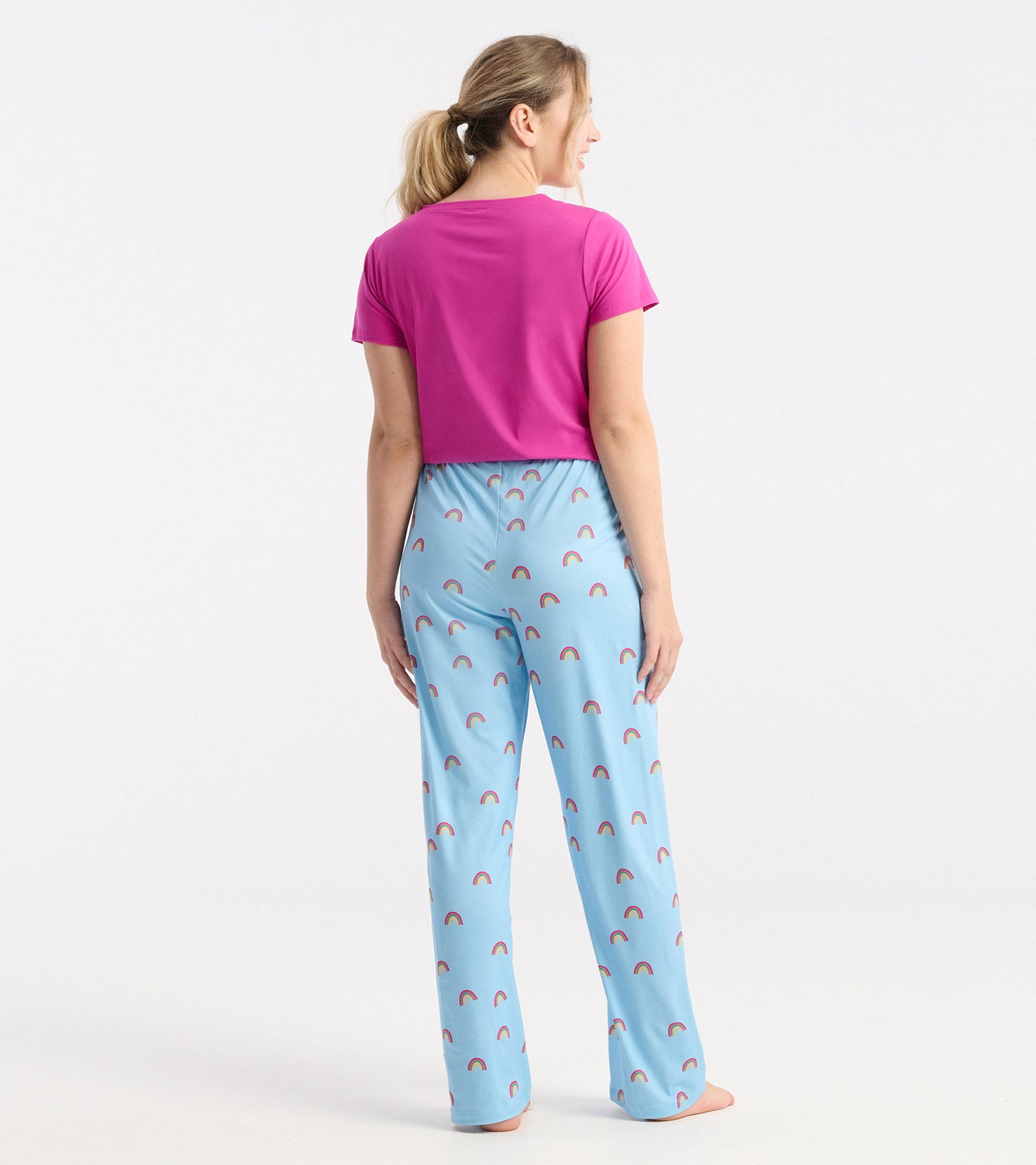 Back view of women's pajama pants in light blue with a rainbow pattern, paired with a pink short-sleeve top.
