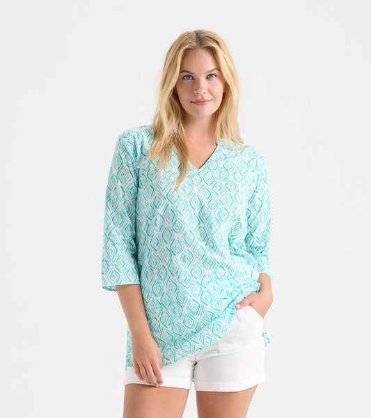 Light teal tunic with diamond pattern, V-neck, and three-quarter sleeves, styled with white shorts.