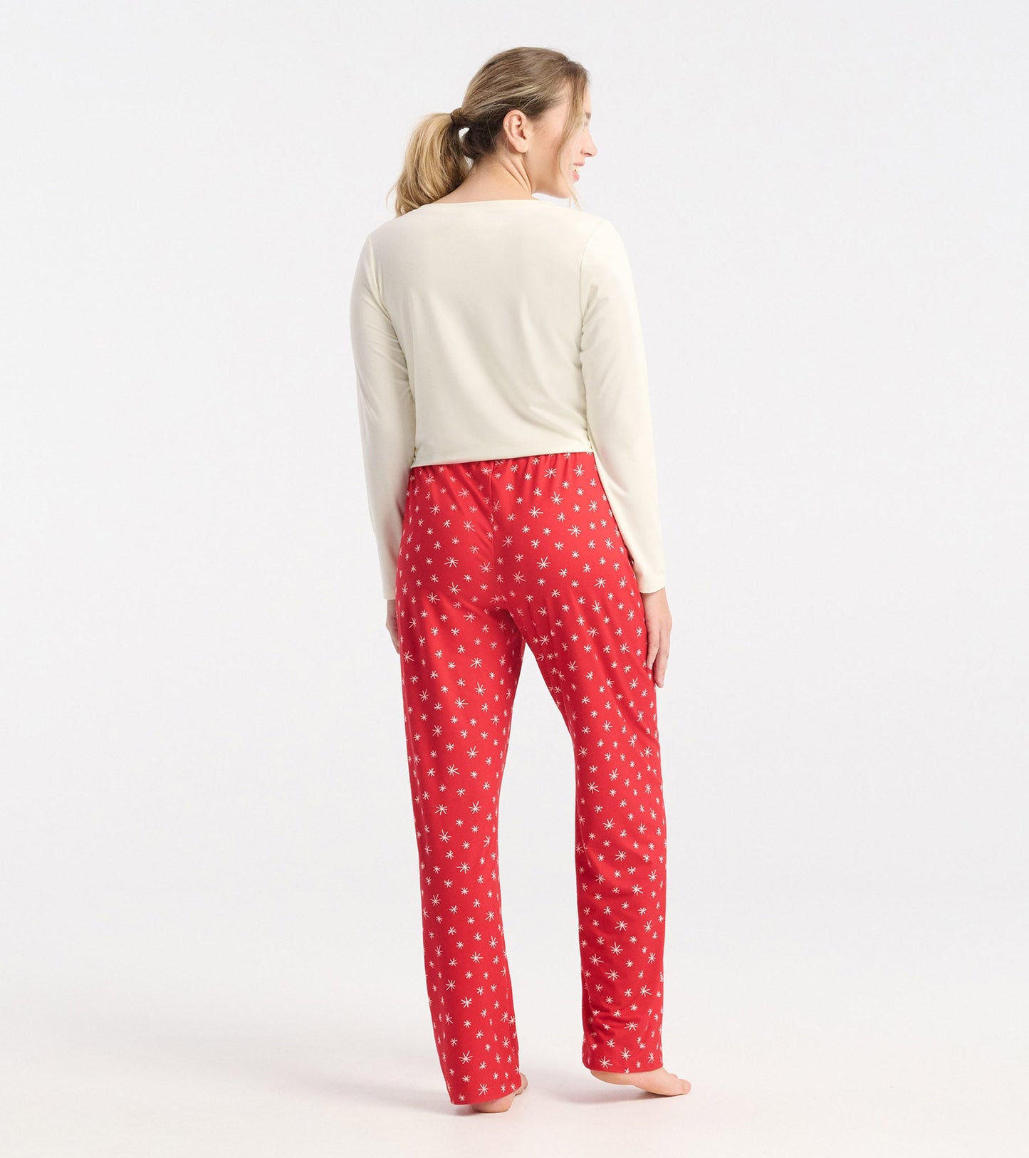 Red polyknit pajama pants featuring a snowflake pattern, shown from the back with a light top.
