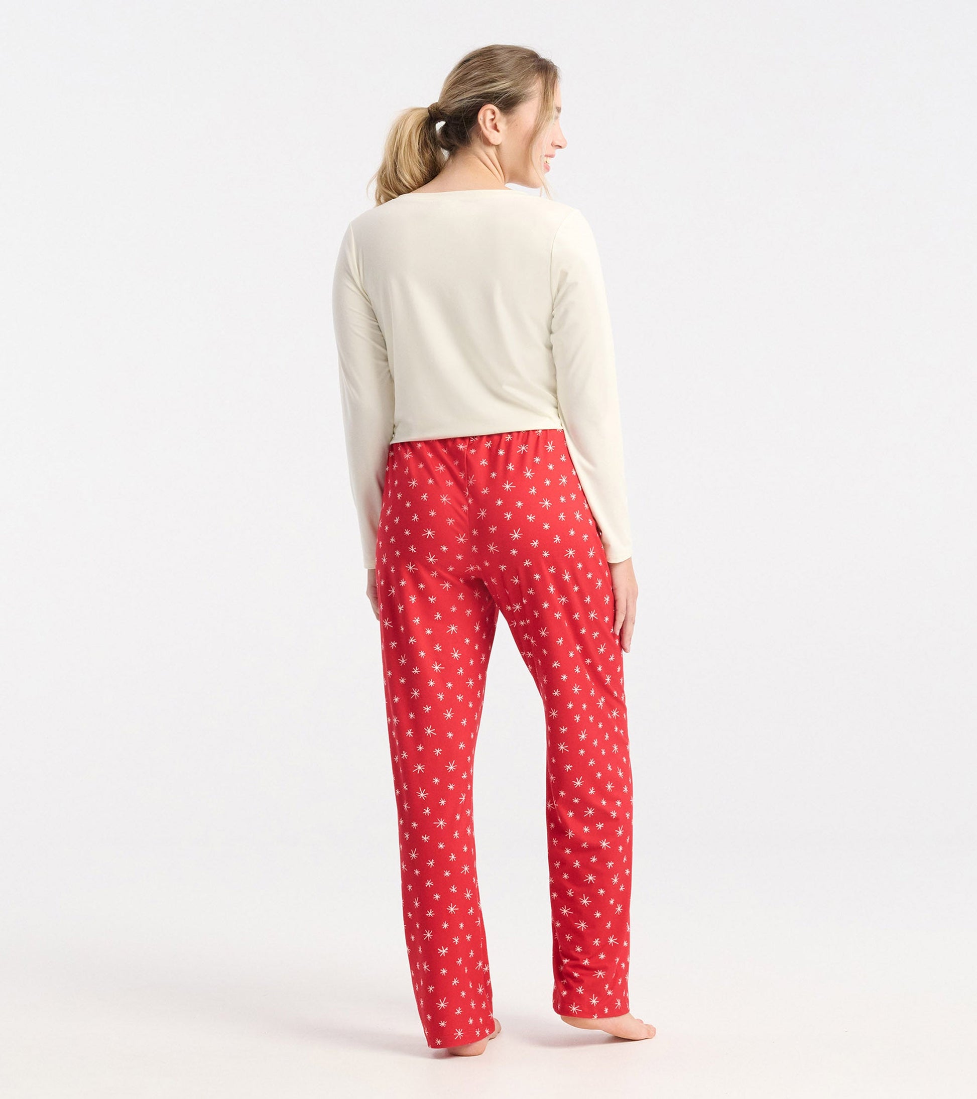 Red polyknit pajama pants featuring a snowflake pattern, shown from the back with a light top.