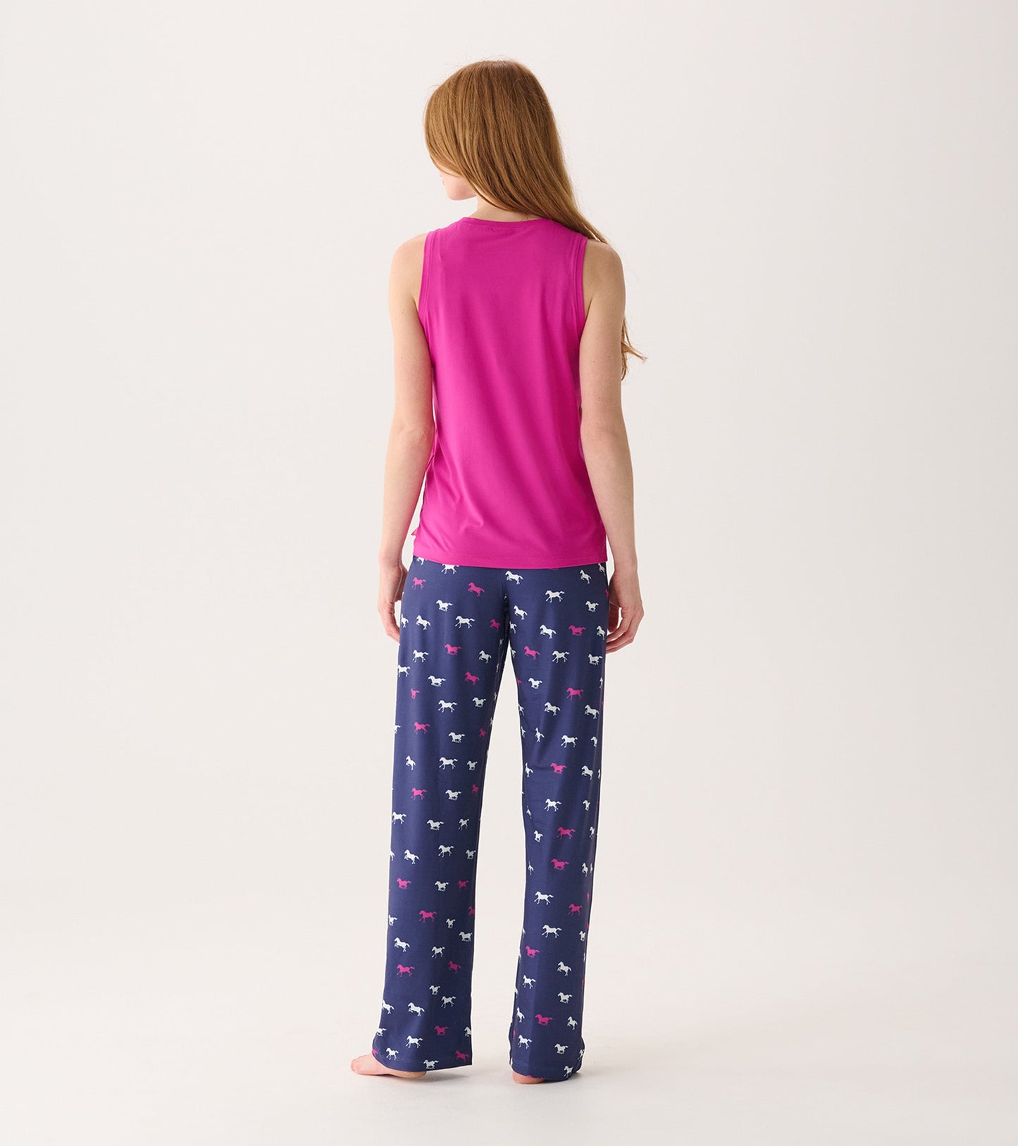 Back view of a women's scoop neck tank top in rose violet, paired with patterned pajama pants.
