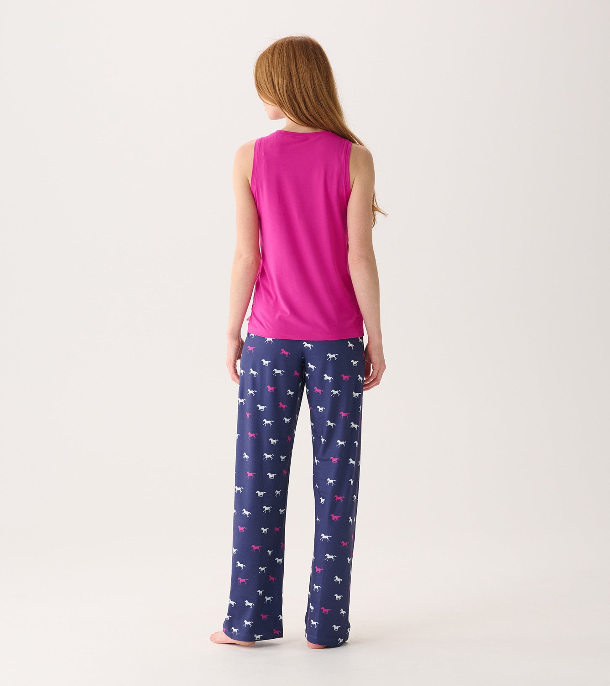 Back view of a women's scoop neck tank top in rose violet, paired with patterned pajama pants.