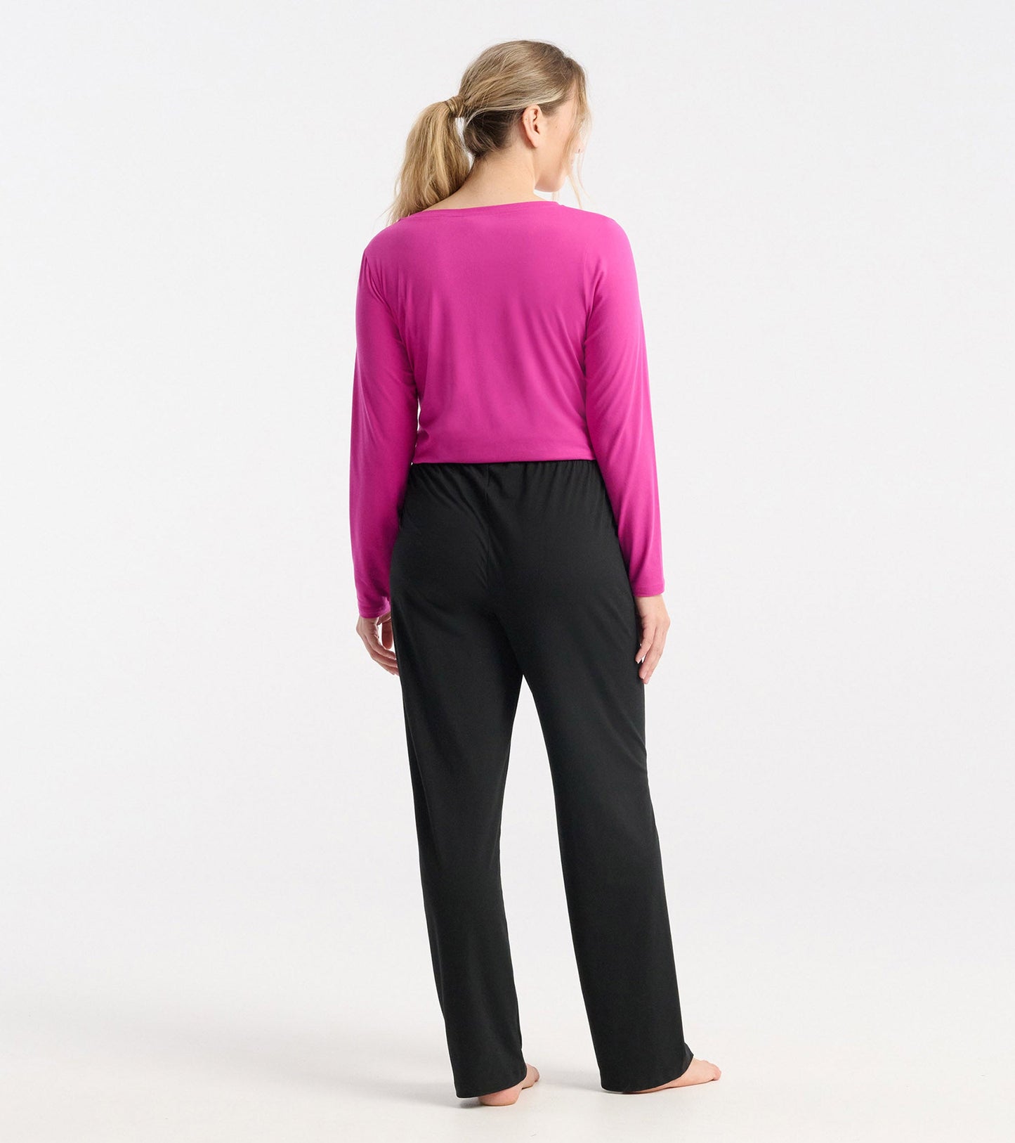 Long sleeve t-shirt in rose violet polyknit, viewed from the back, paired with black pants.