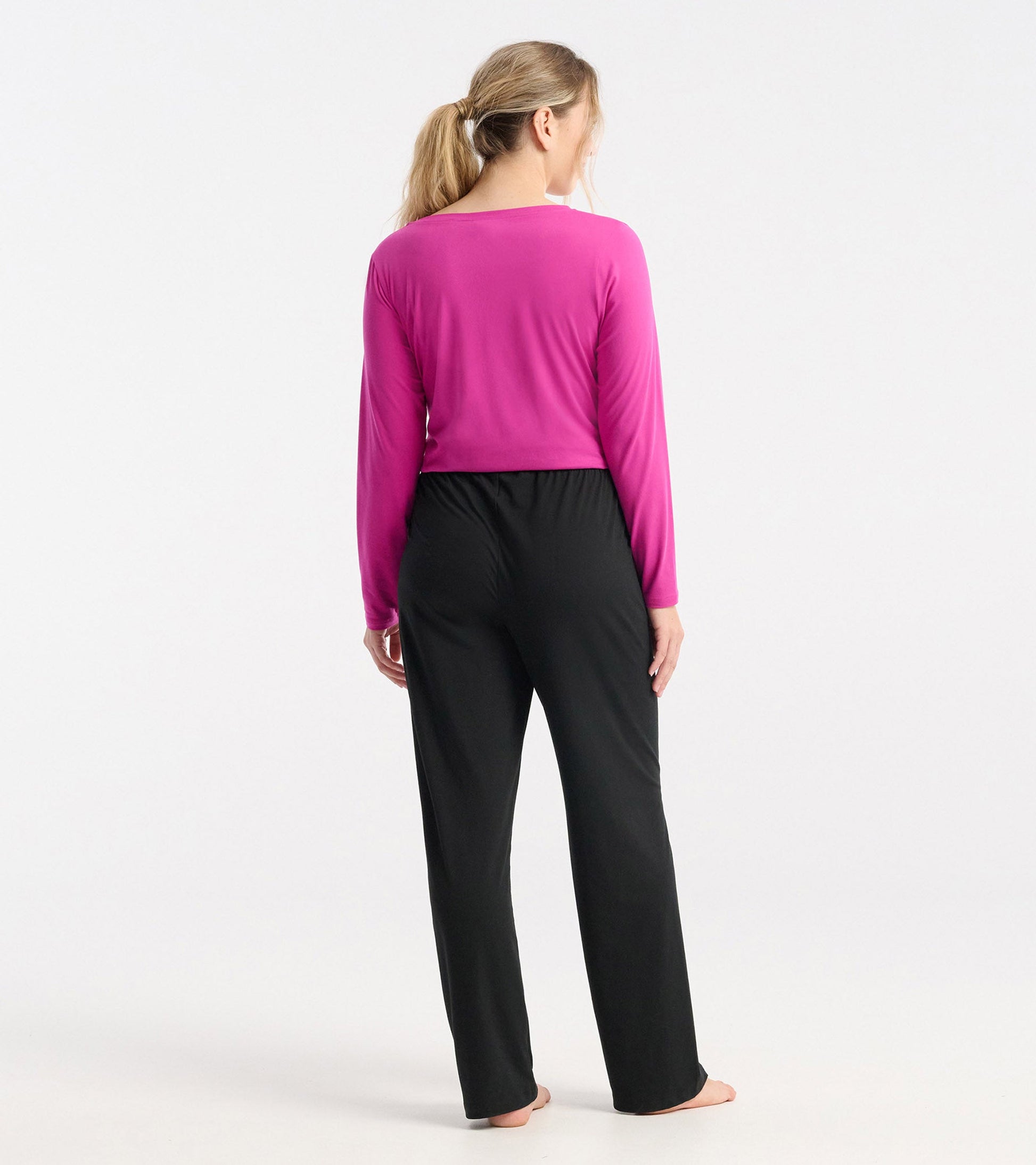 Long sleeve t-shirt in rose violet polyknit, viewed from the back, paired with black pants.