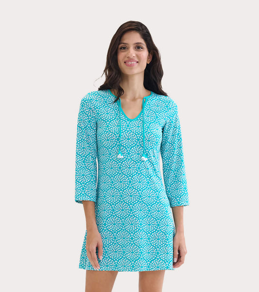Turquoise beach dress with a playful white pattern, three-quarter sleeves, and a V-neck with drawstring detail.