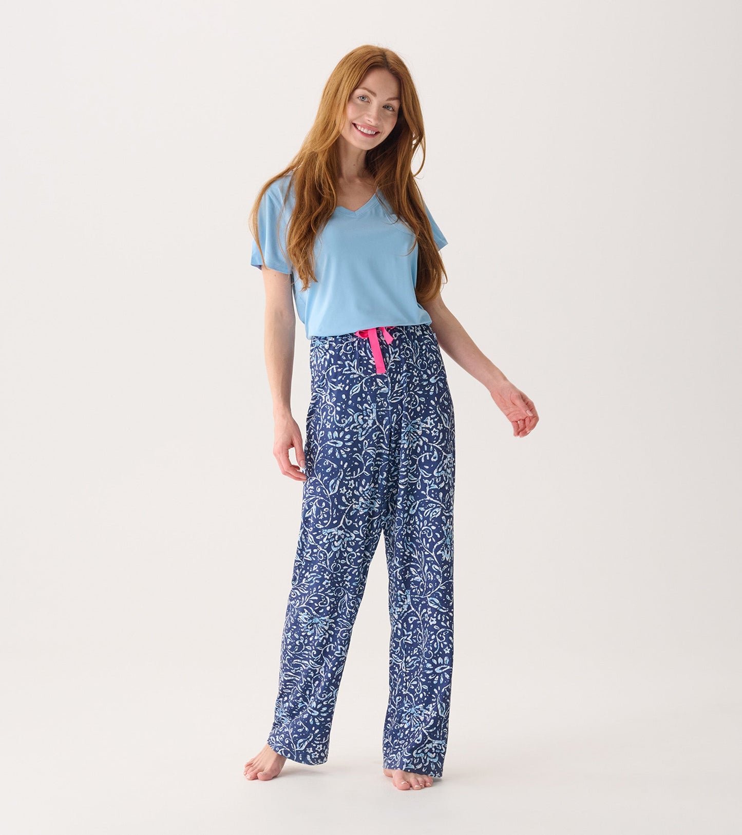 Navy blue pajama pants with a floral batik pattern and a pink drawstring, styled with a light blue top.