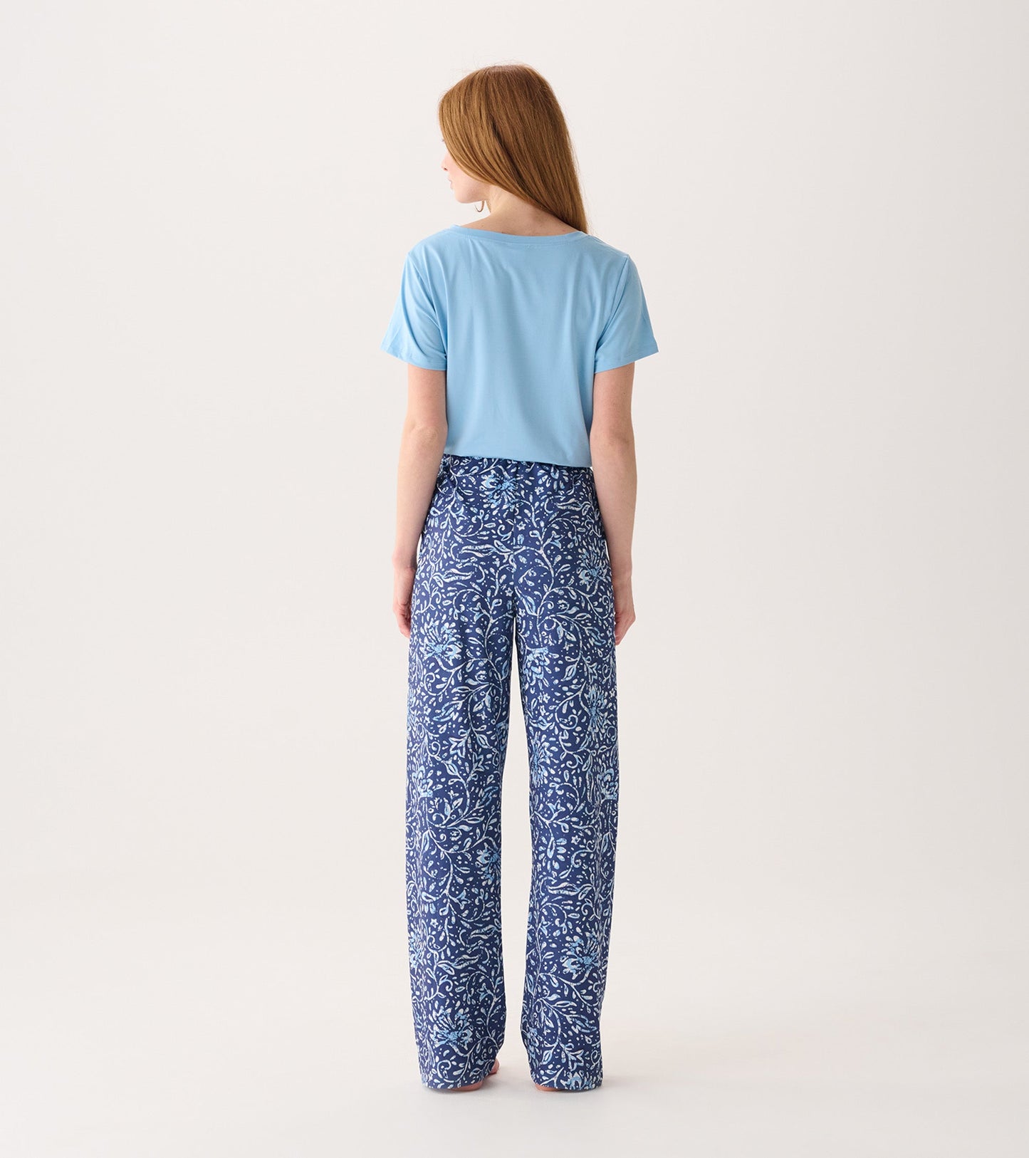 Light blue top paired with flowy blue pajama pants featuring a floral batik pattern, viewed from the back.