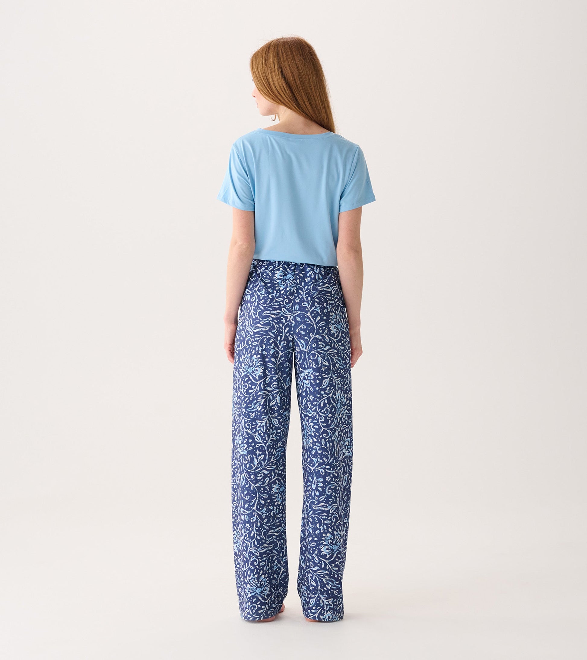 Light blue top paired with flowy blue pajama pants featuring a floral batik pattern, viewed from the back.