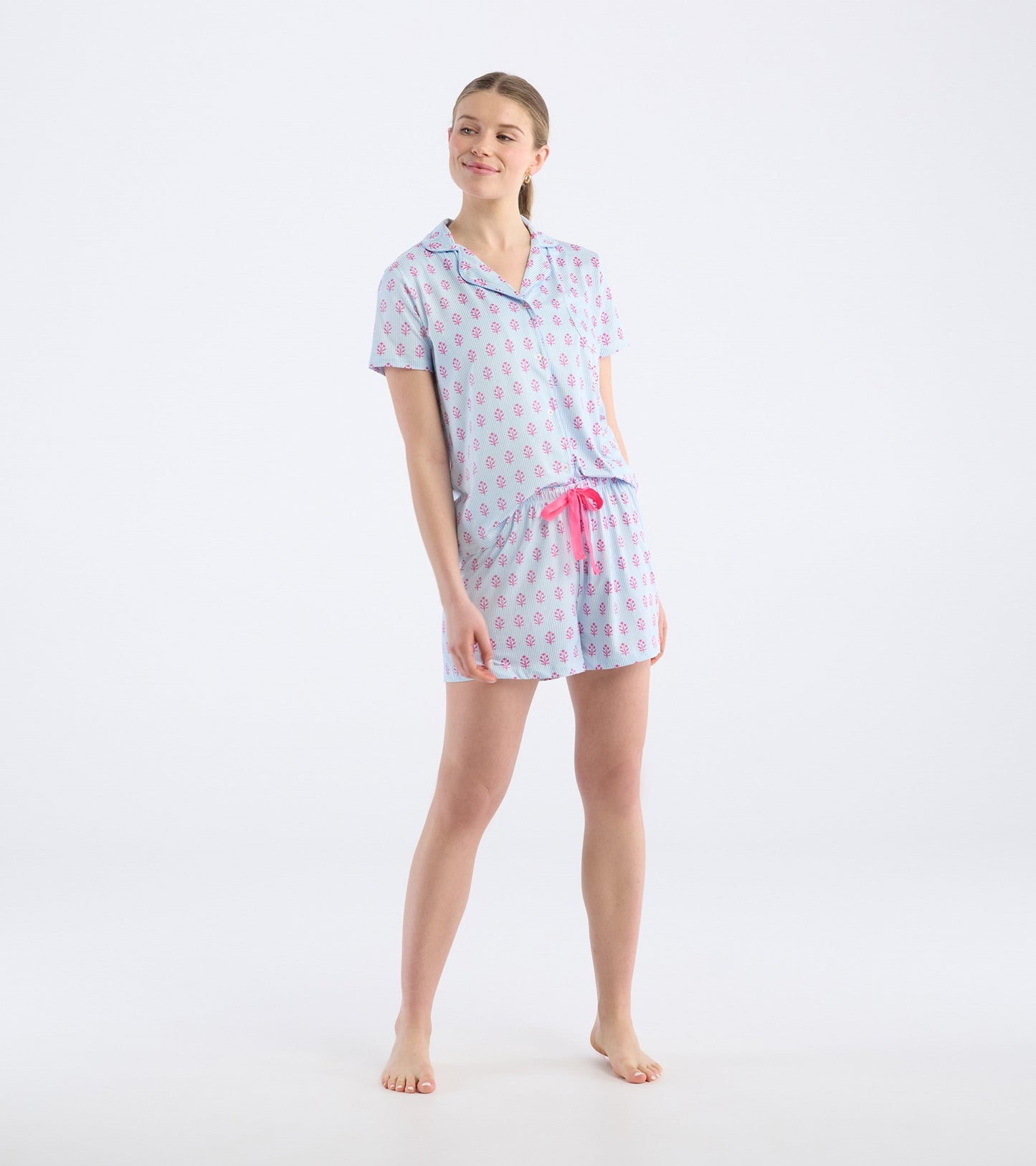 Short pajama set featuring a light blue background with pink floral patterns and a pink drawstring waist.