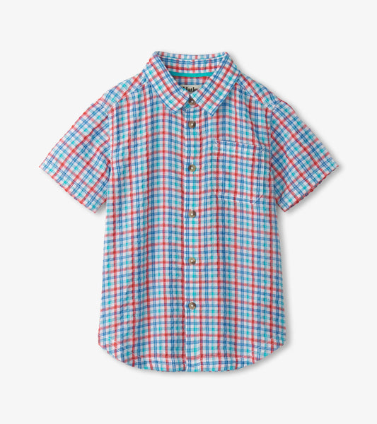 Short-sleeve button-down shirt in blue, red, and white plaid pattern with a chest pocket.