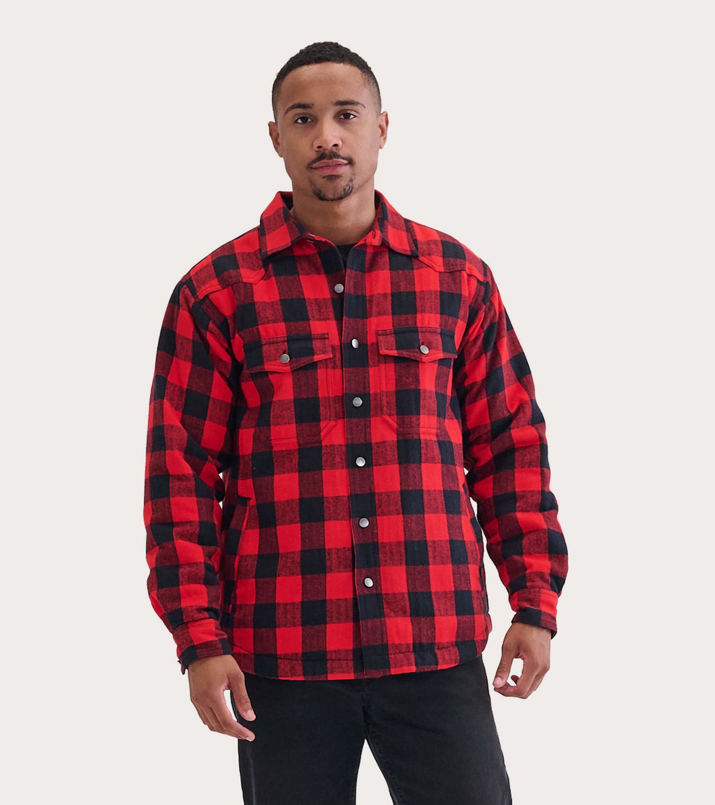 Red and black buffalo plaid quilted jacket with button closure and two chest pockets, worn by a model.