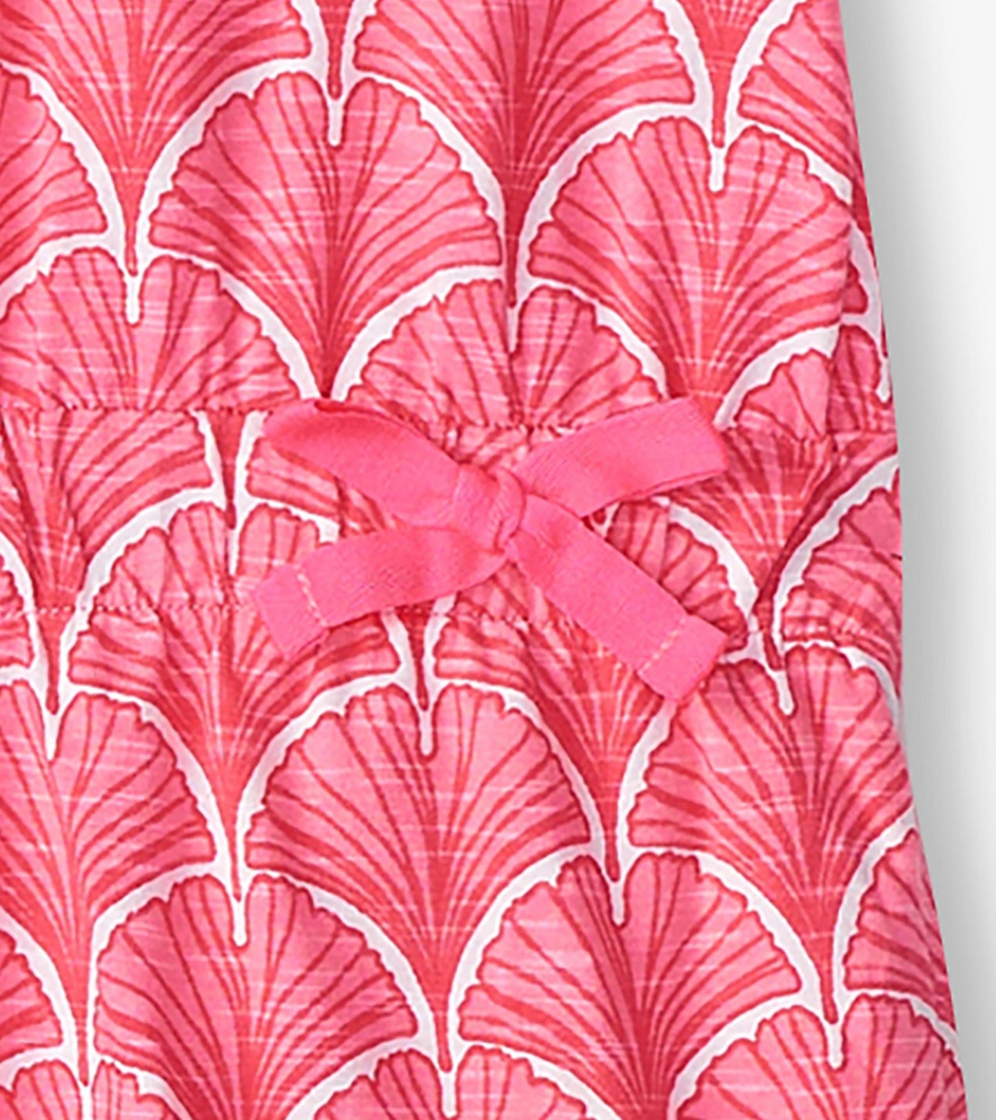 Coral t-shirt dress featuring a fan pattern and a pink bow detail at the waist.