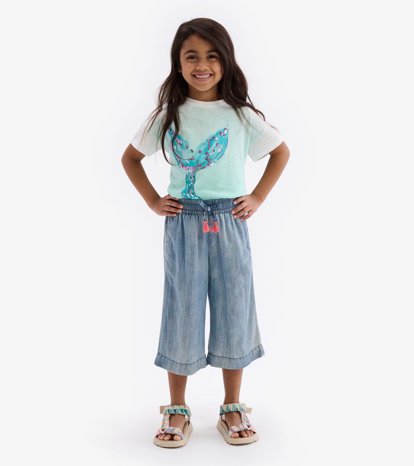 Light teal boxy tee featuring a colorful whale graphic, paired with denim culottes and sandals.