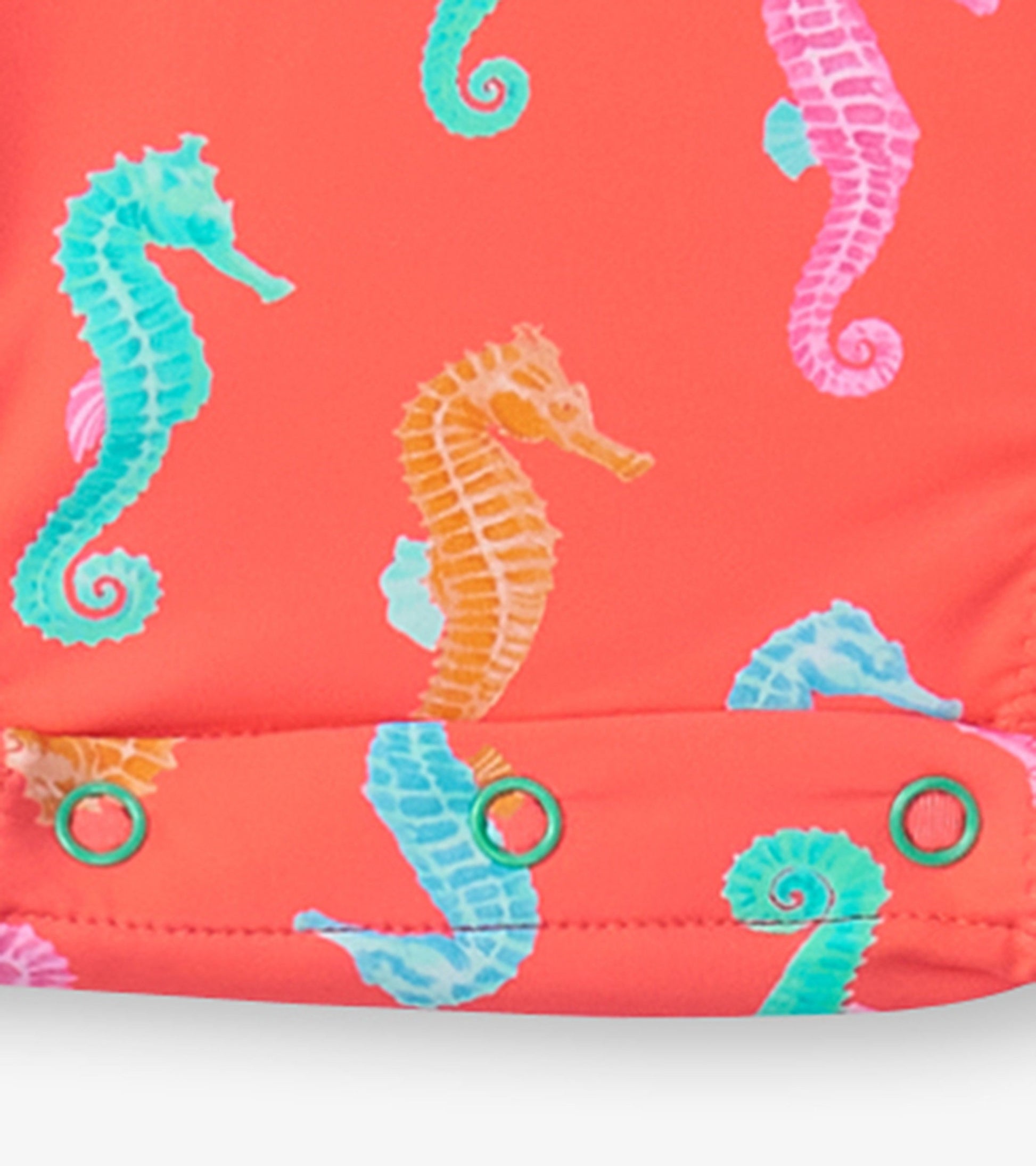 Coral rashguard swimsuit for baby girls featuring colorful seahorse prints and snap closures at the bottom.