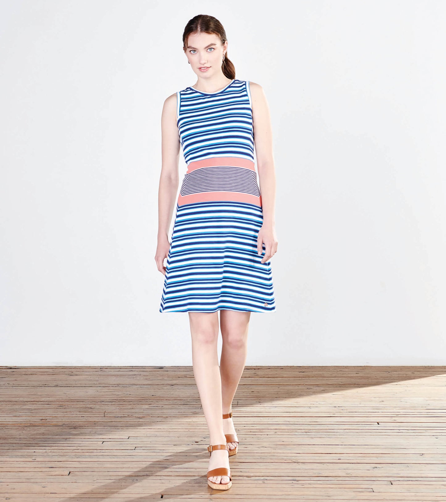 Sleeveless dress featuring blue and white stripes with a coral waistband, flaring out gently at the hem.