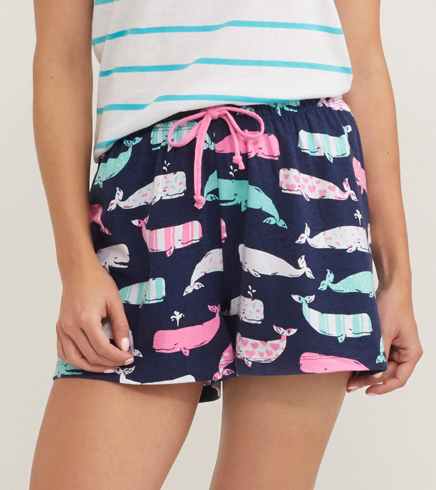 Navy cotton sleep shorts featuring a playful whale print in pink, white, and teal, with an elastic waistband and drawstring.