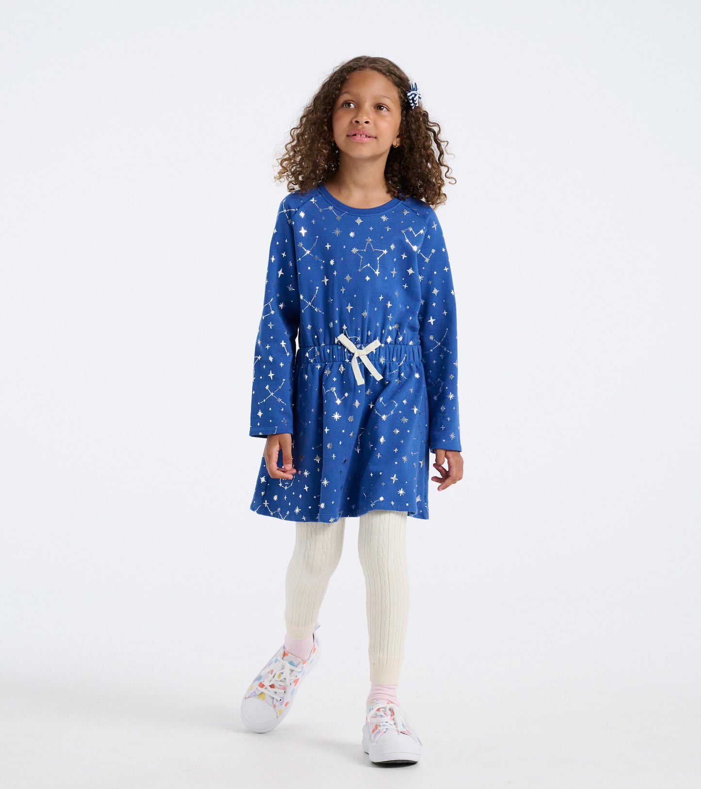 Blue terry dress with constellation print, long sleeves, and a cinched waist, paired with cream leggings and colorful shoes.