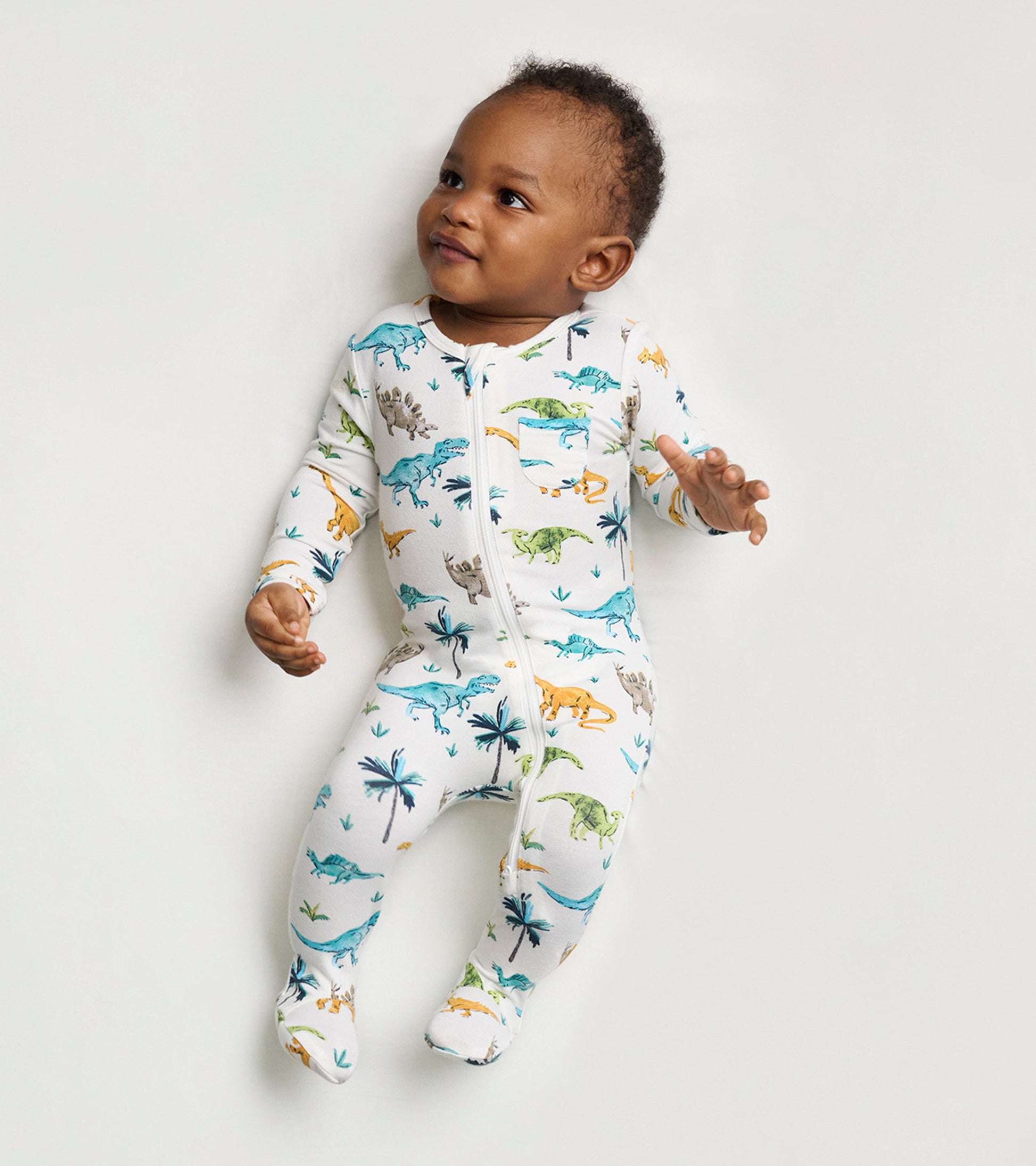 White footed sleeper featuring colorful dinosaur prints, designed for baby boys, with a front zipper and long sleeves.