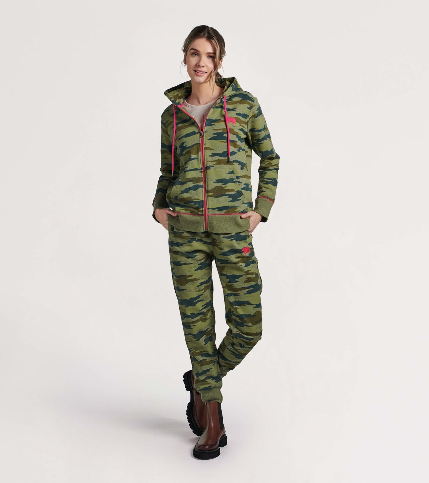 Green woodland camo full zip hoodie with pink accents, featuring a hood and front pockets, styled with matching pants.