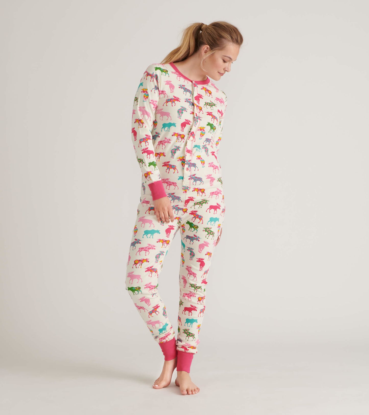 Adult onesie featuring a colorful moose pattern on a cream background, with pink cuffs and buttons.