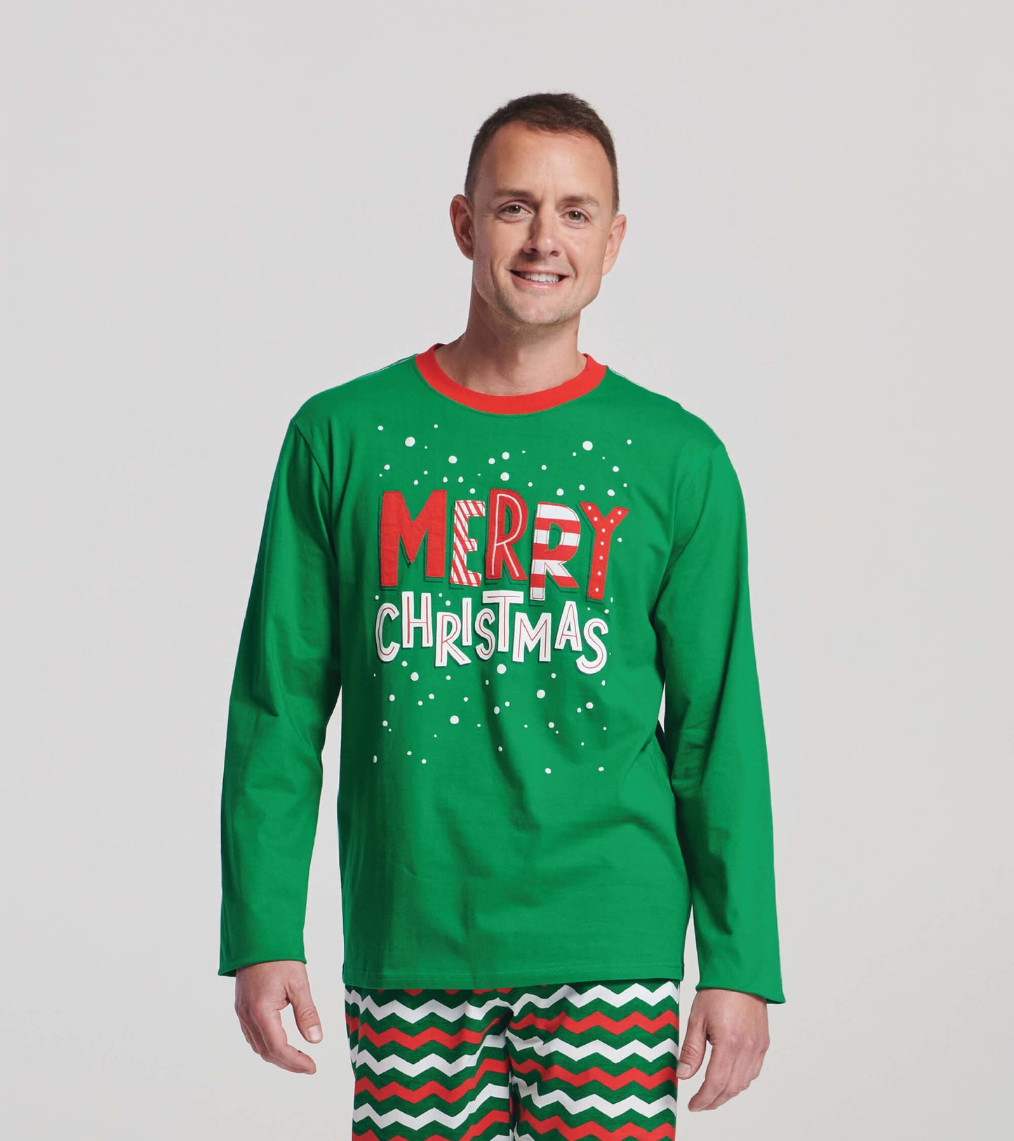 Green long sleeve t-shirt featuring "MERRY CHRISTMAS" graphic in red and white, perfect for festive occasions.