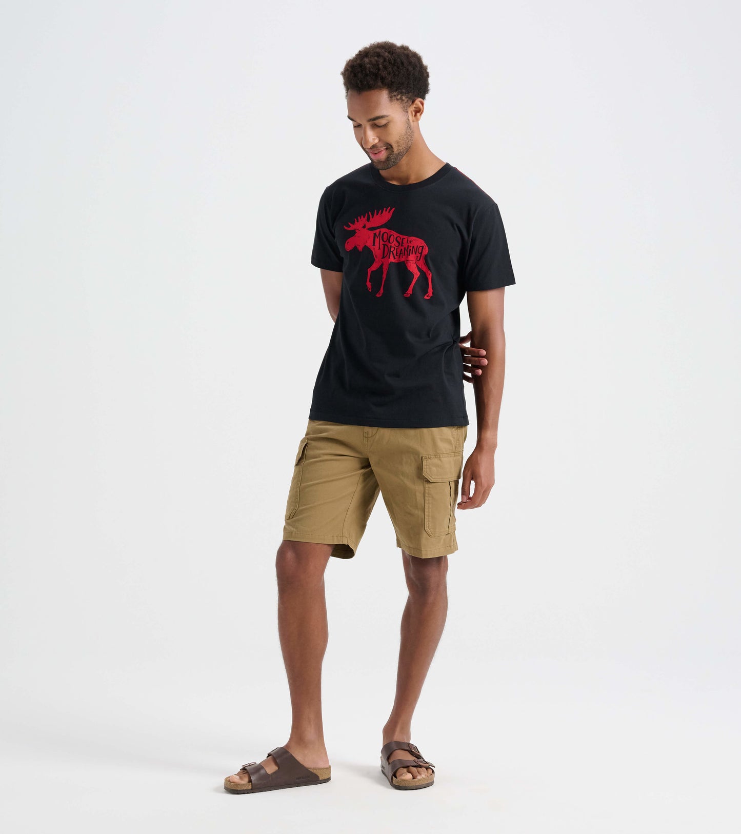 Black men's t-shirt featuring a red moose graphic, worn with khaki shorts and sandals.