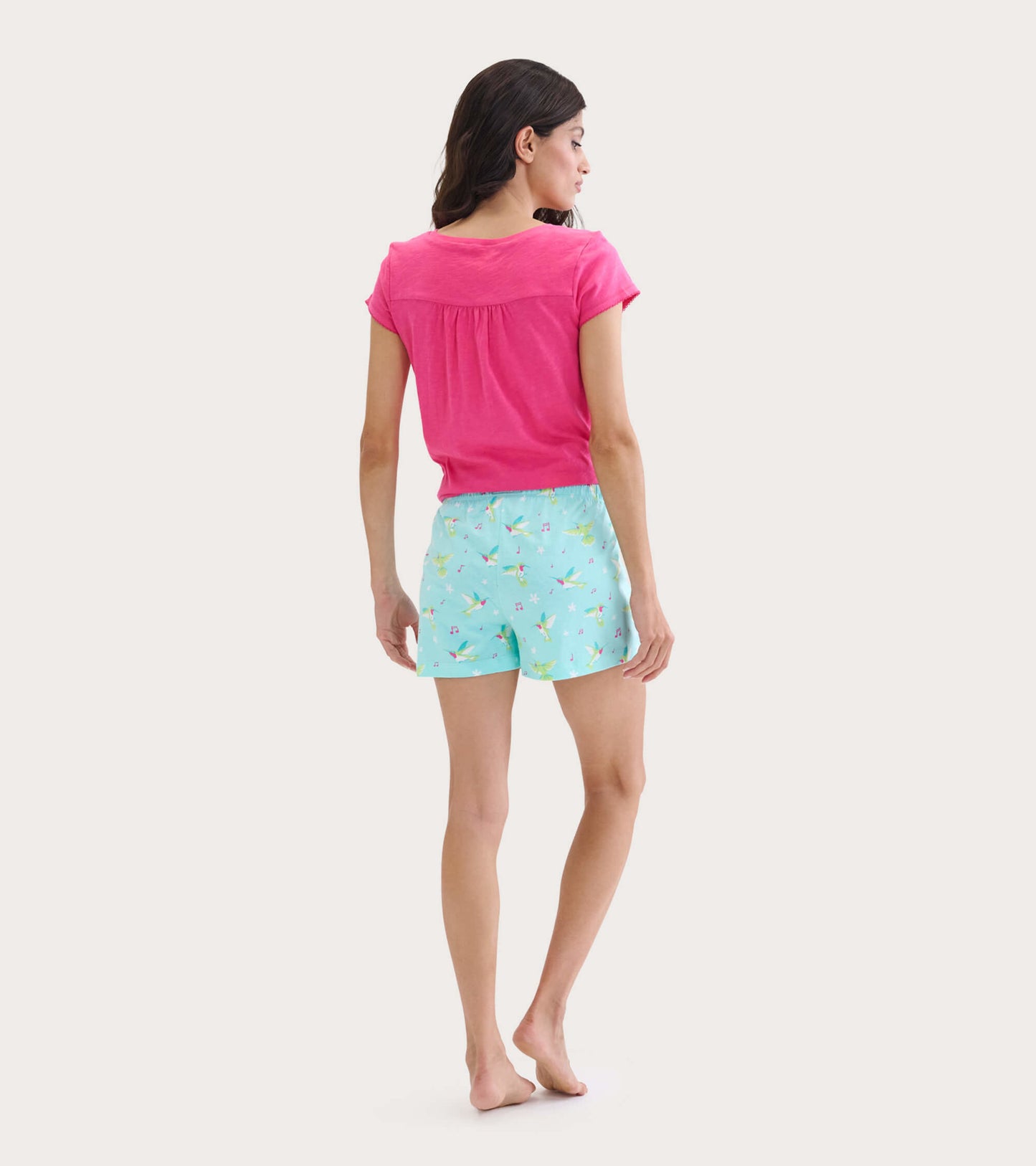 Pink V-neck tee with short sleeves, paired with light blue shorts featuring a floral pattern, shown from the back.
