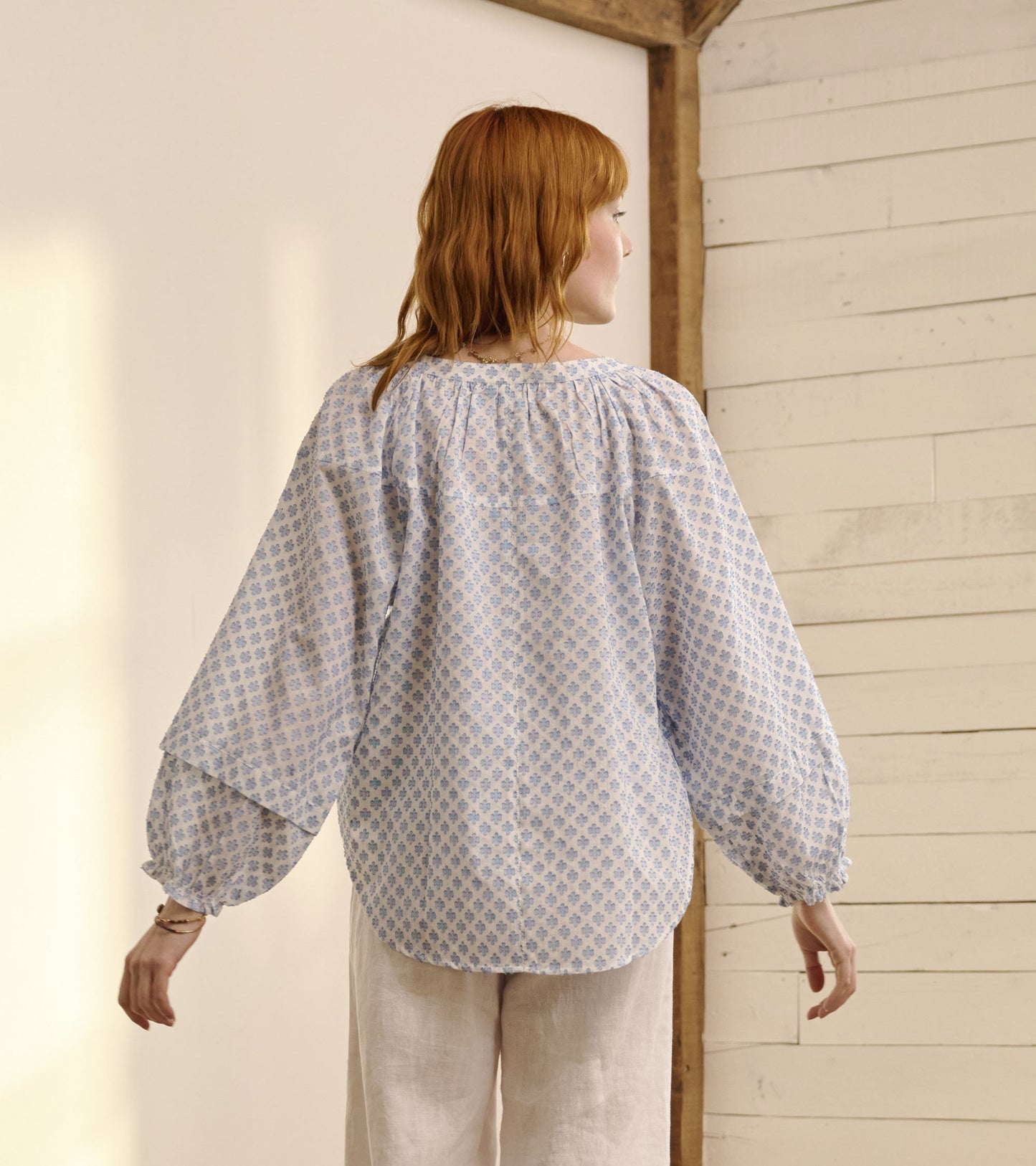 Light blue blouse with floral pattern, loose fit, and balloon sleeves, viewed from the back.