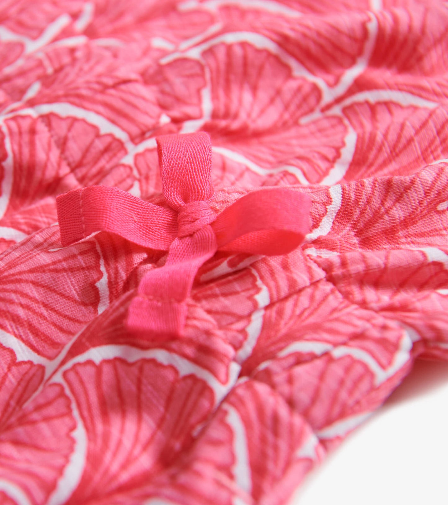 Coral T-shirt dress featuring a fan pattern and a pink bow detail at the waist. Soft fabric suitable for casual wear.