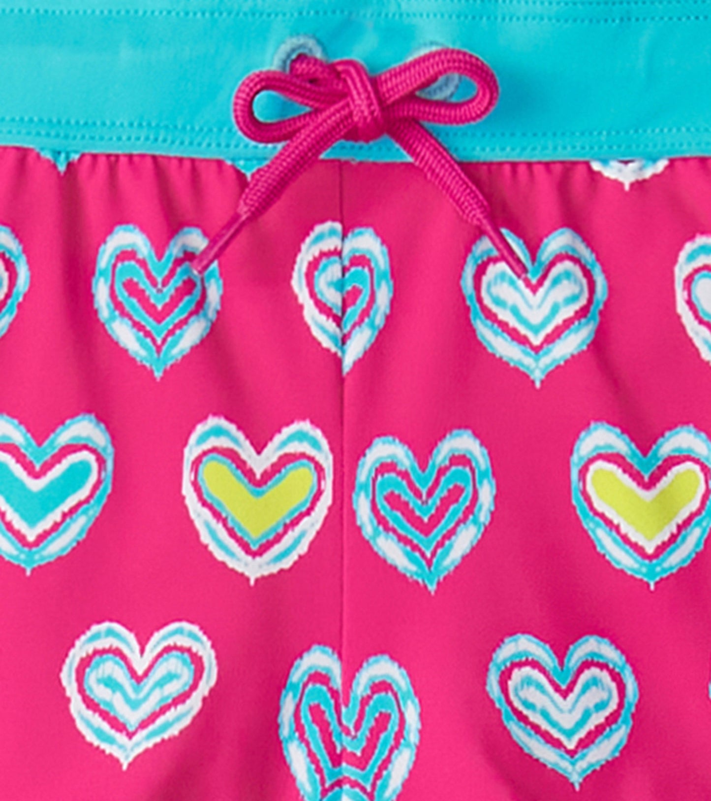 Girls' pink swim shorts featuring a colorful heart pattern and a turquoise waistband with a drawstring.