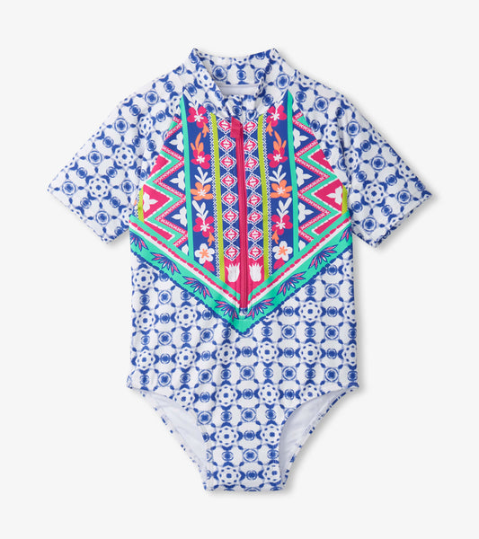 Short-sleeve one-piece rashguard in blue with colorful floral and geometric patterns, featuring a front zipper.