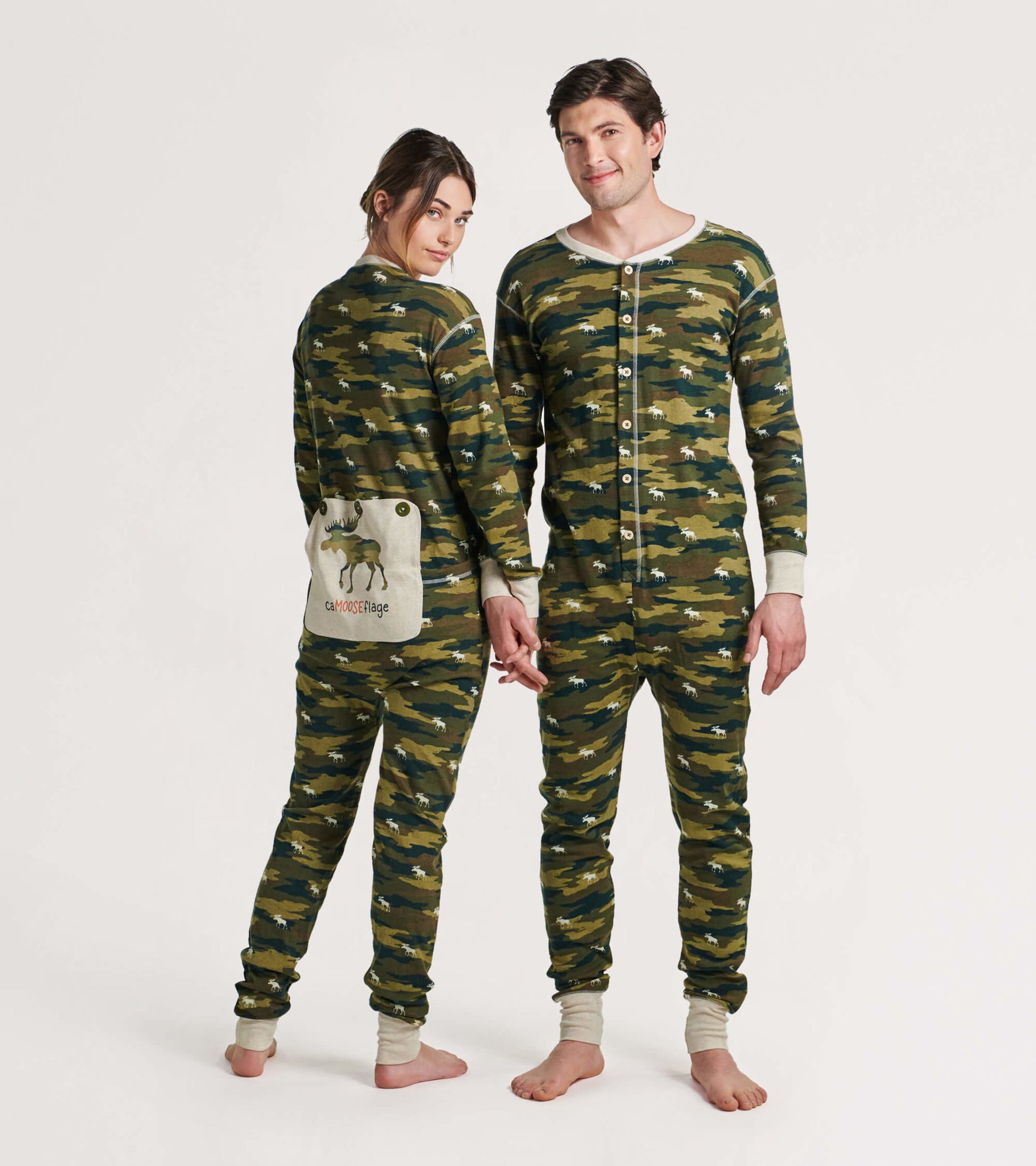Camo-patterned adult onesie in green tones, featuring a button front and a moose graphic on the back pocket.