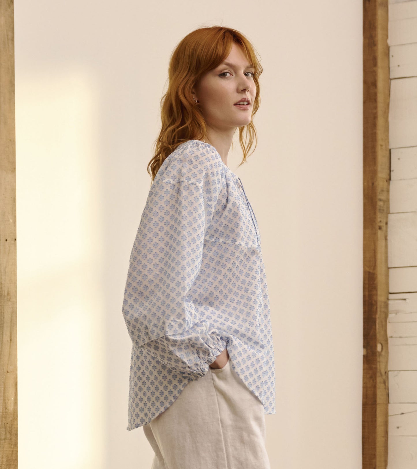 Light blue blouse with floral pattern, long sleeves, and a relaxed fit, styled with neutral pants.