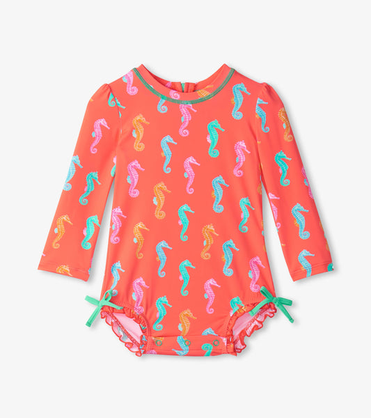 Coral rashguard swimsuit for baby girls with colorful seahorse pattern and ruffled trim, featuring long sleeves and ties.