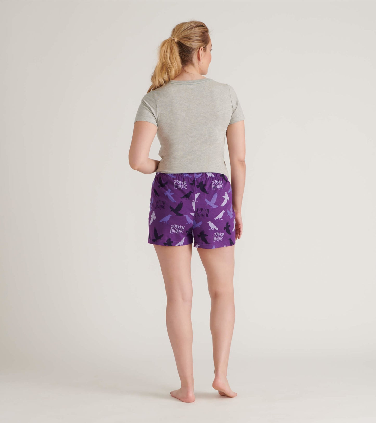 Purple cotton sleep shorts featuring a bird pattern, elastic waistband, and a relaxed fit, shown from the back.