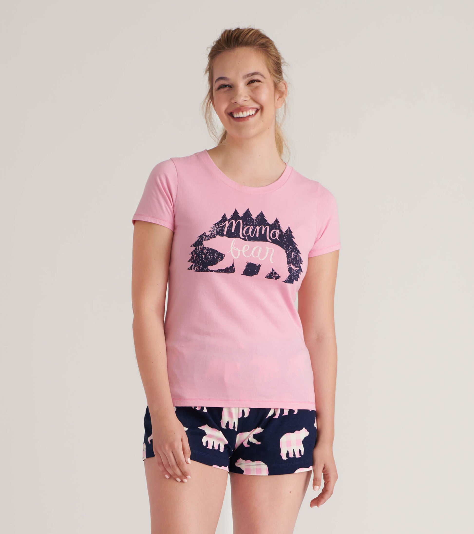 Pink short-sleeve pajama t-shirt featuring a bear graphic and text, paired with navy shorts with bear patterns.