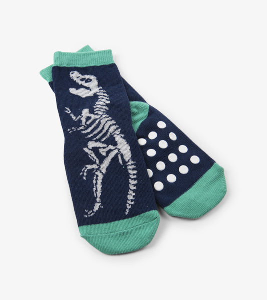 Navy socks featuring a white dinosaur skeleton design and green accents, with non-slip polka dots on the sole.