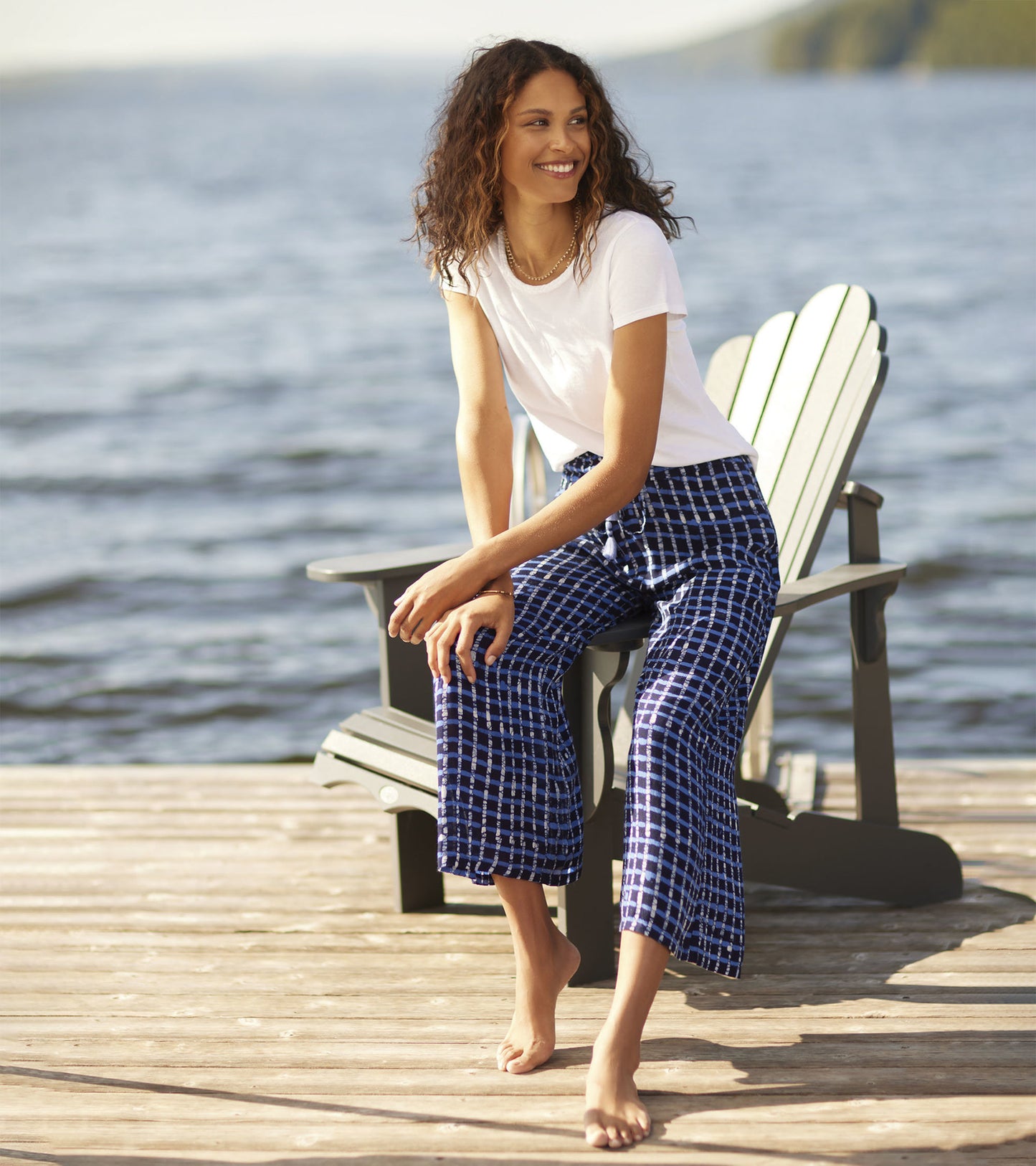 Navy plaid cropped pants with a relaxed fit, styled with a white t-shirt, worn by a woman sitting by the water.