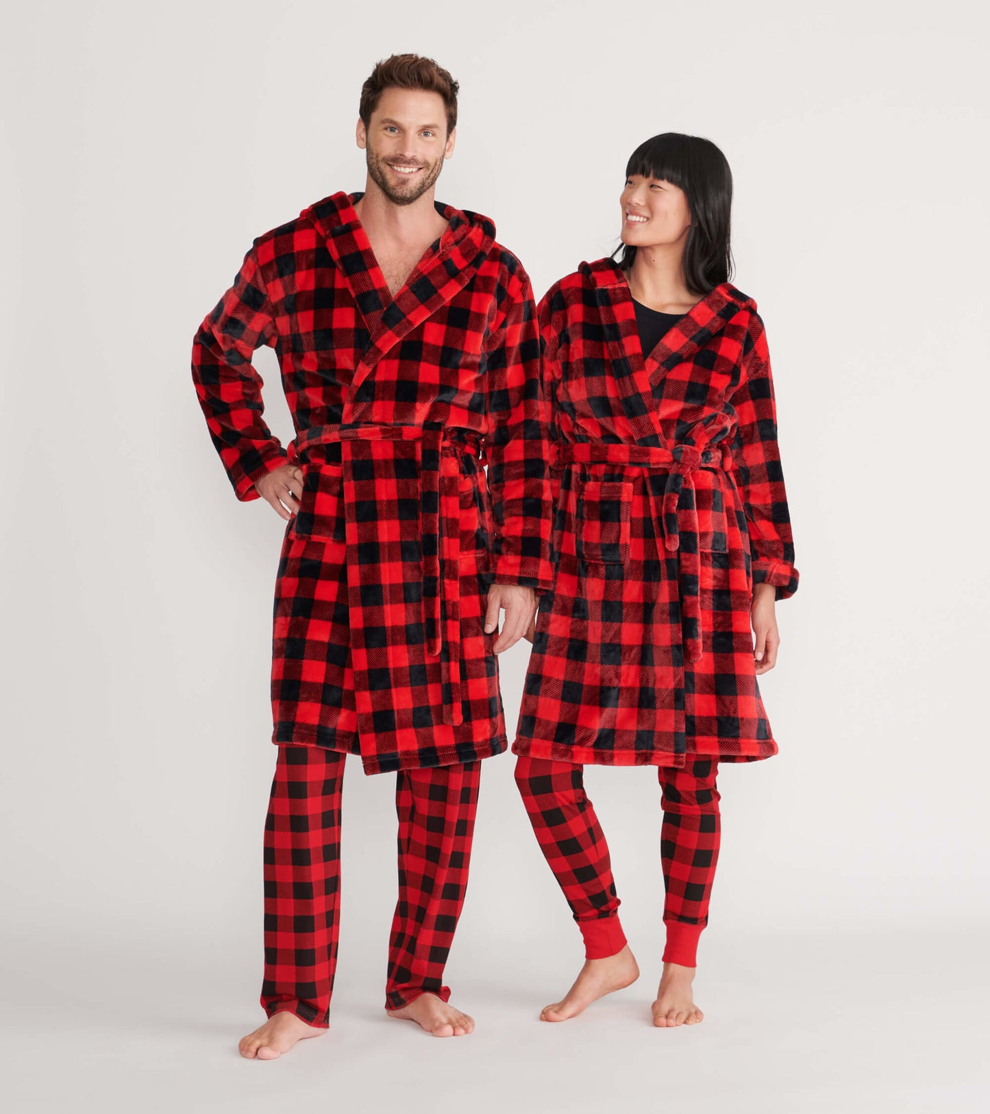 Red and black buffalo plaid fleece robe on two models, featuring a hood and tie waist, suitable for lounging.