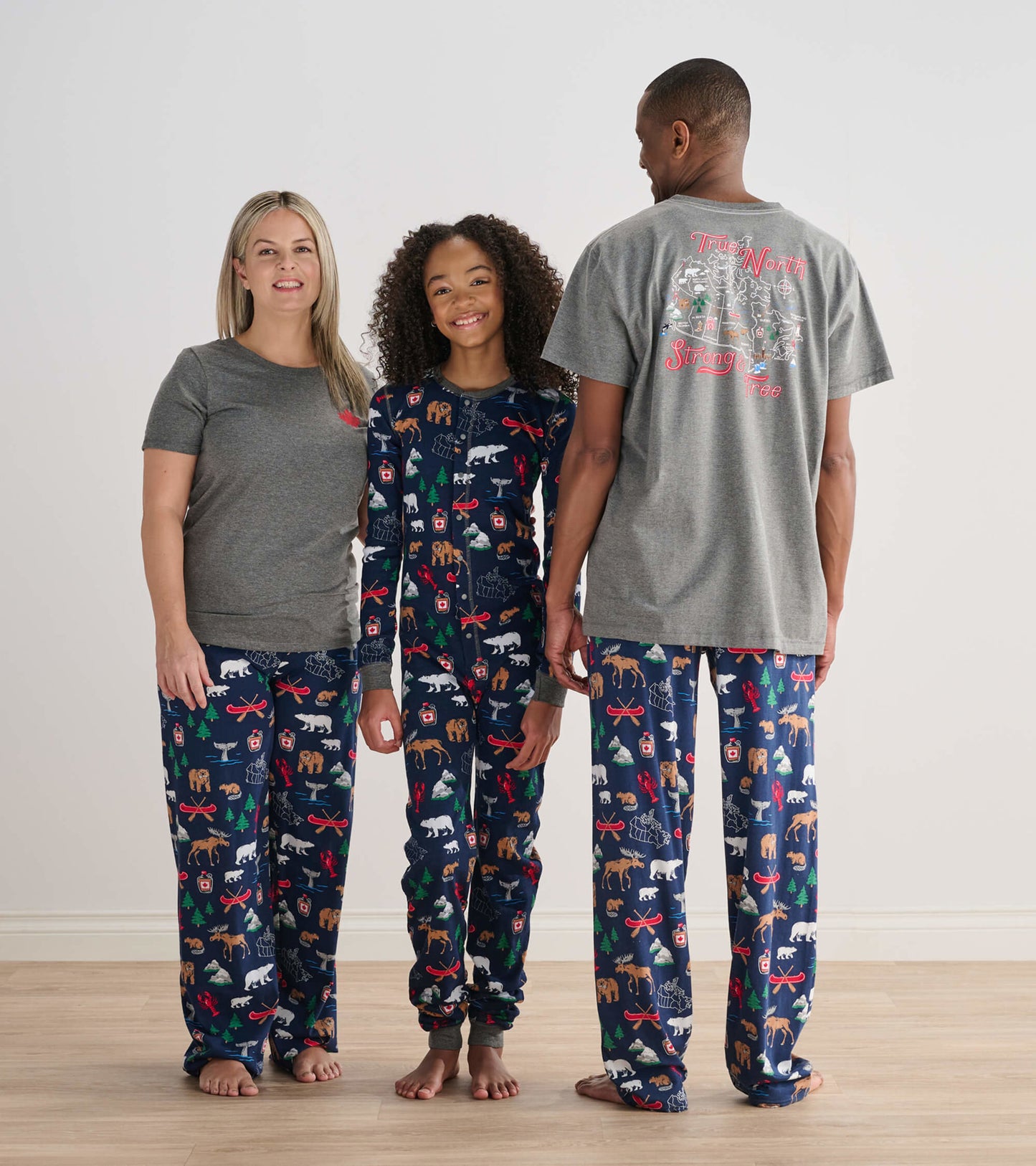 Family wearing matching pajama sets with a navy blue pattern featuring animals and trees, made from soft fabric.