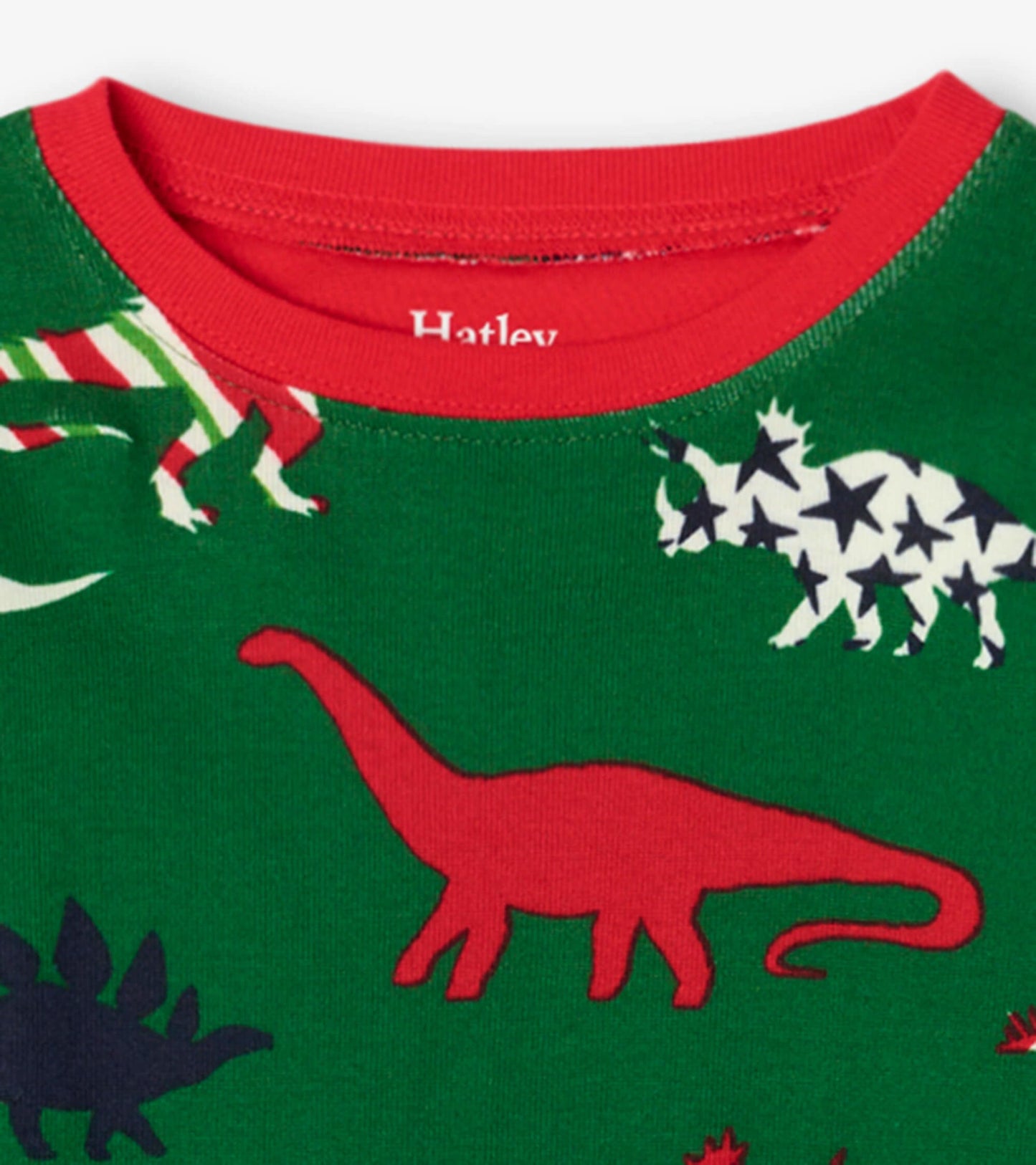 Green organic cotton pajama top with red trim featuring colorful dinosaur patterns.