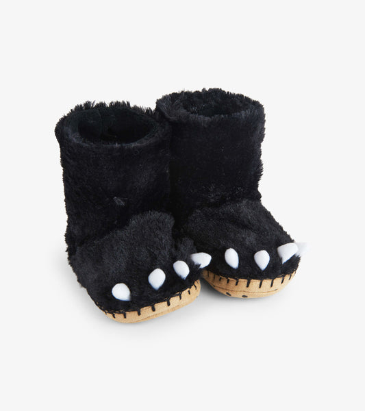 Black fuzzy slouch slippers shaped like bear paws with white claws and a soft interior, suitable for kids.
